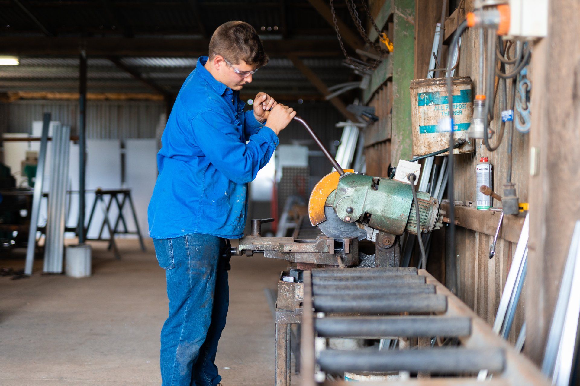 Worker in blue jacket using a grinder on metal in an industrial workshop