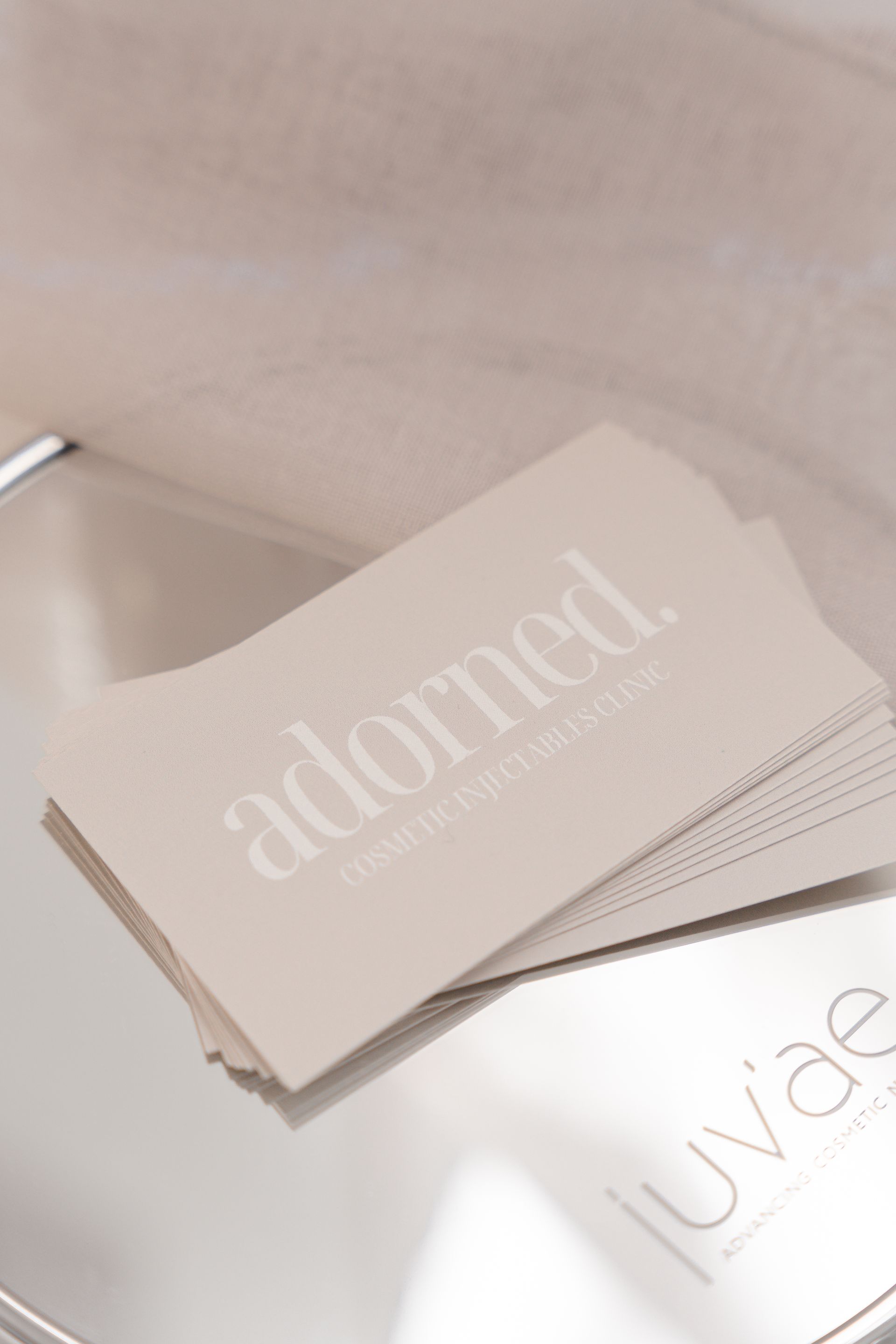 Two stacked product cards on a beige surface, one reading “adorned” and another “luna”