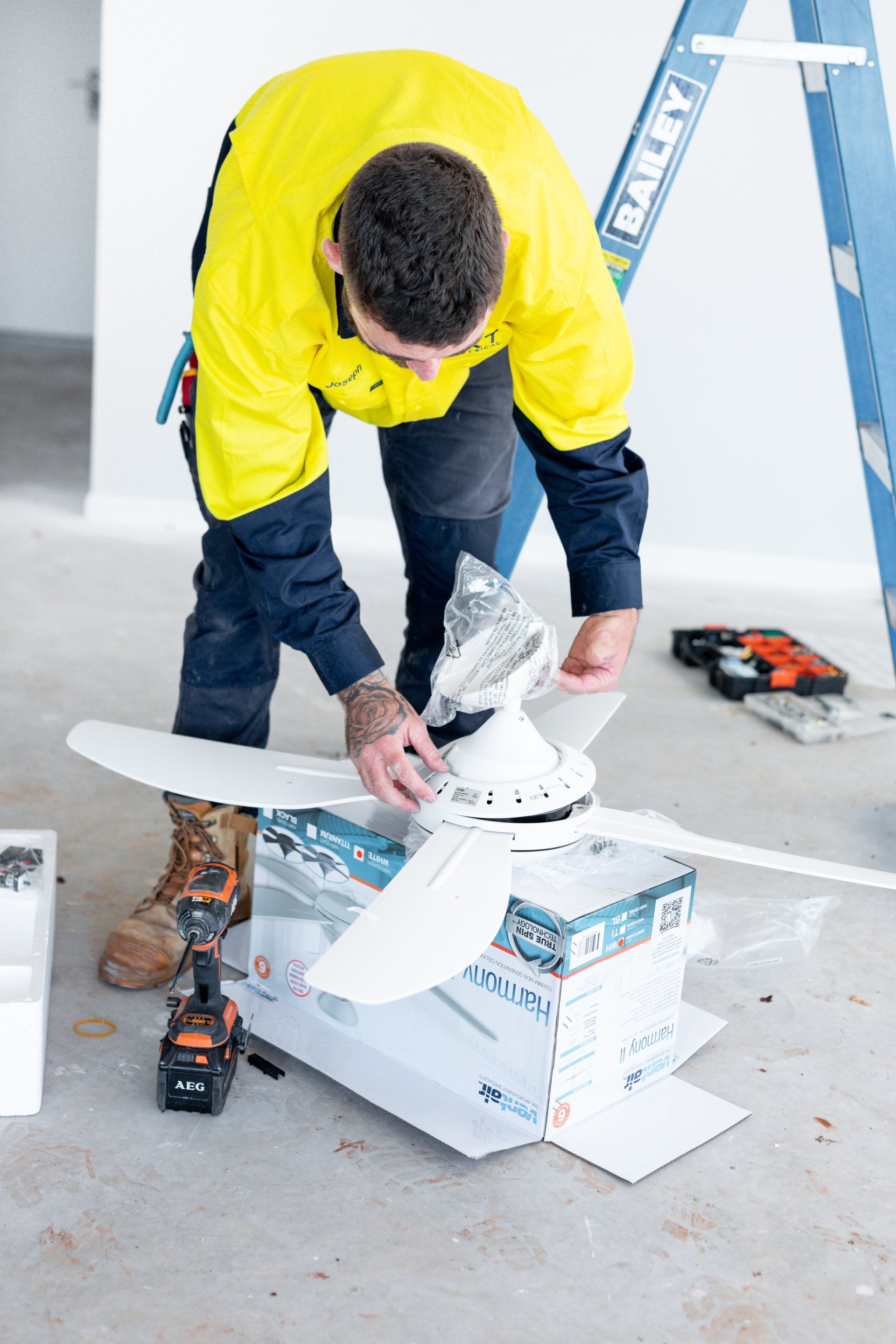 Worker in yellow jacket fixing a snowboard on a workbench with tools nearby
