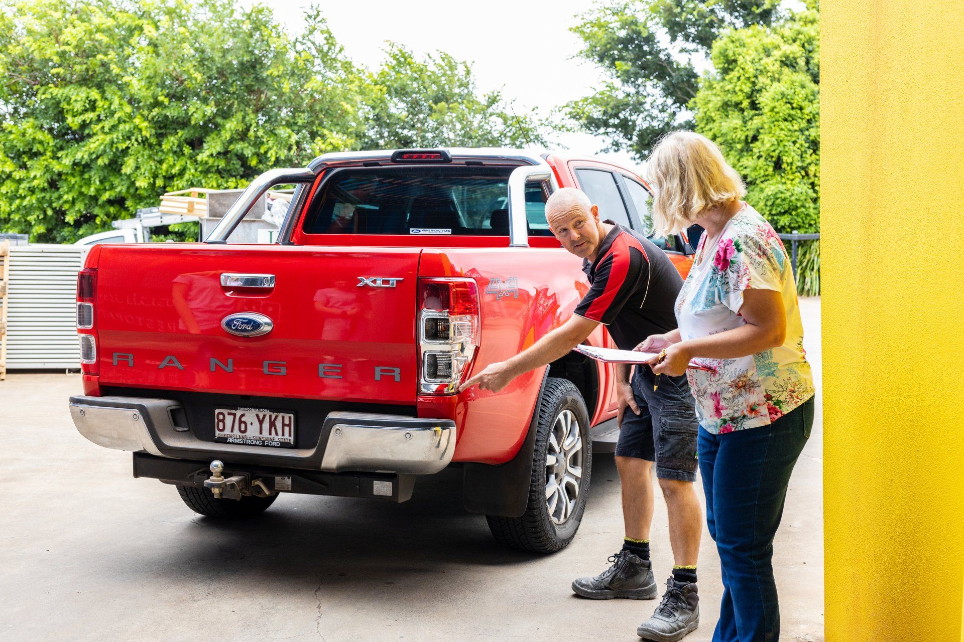 Two people loading a red pickup truck in a driveway