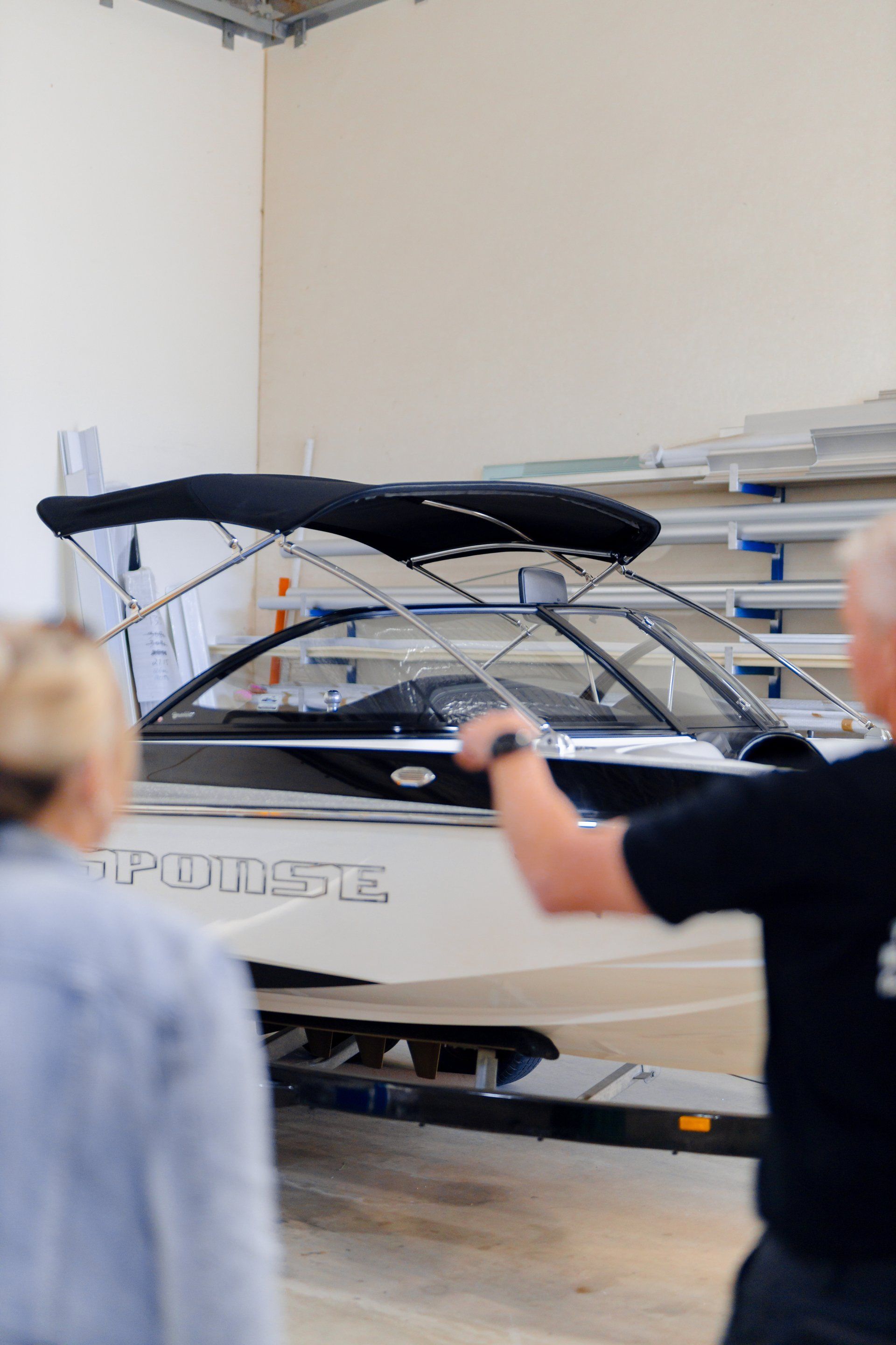 People loading a white boat onto a trailer inside a garage