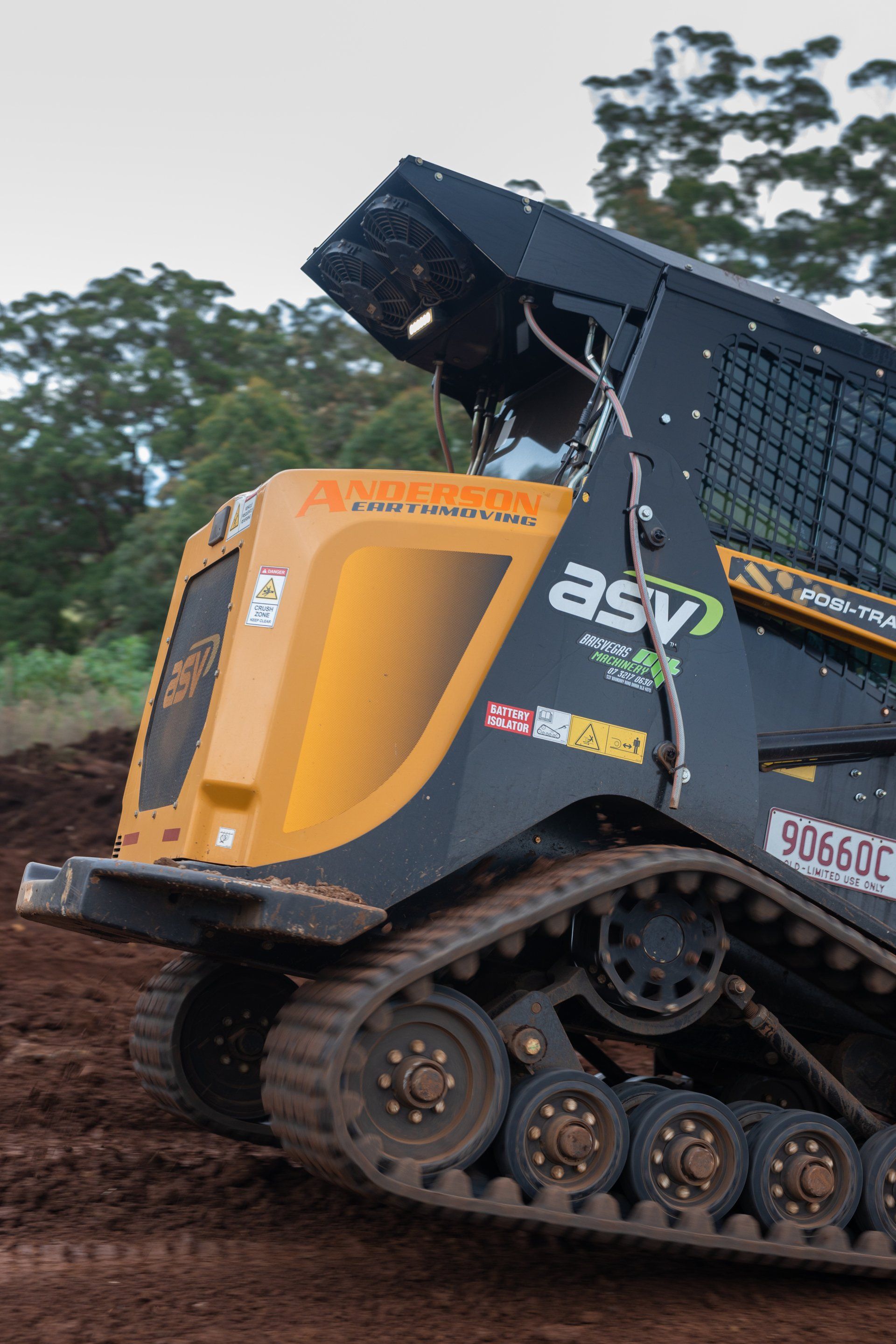 Yellow ASV tracked construction vehicle climbing muddy terrain outdoors