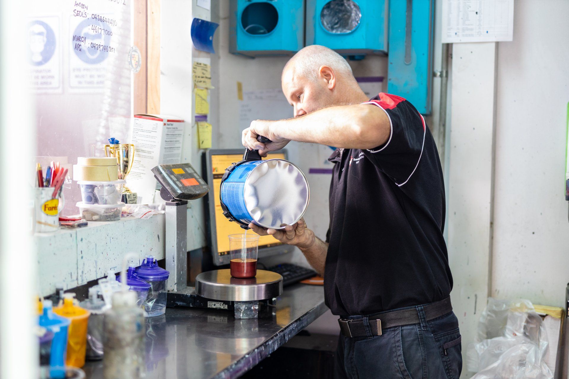 Man pouring liquid into a machine in a bright industrial kitchen or food prep area