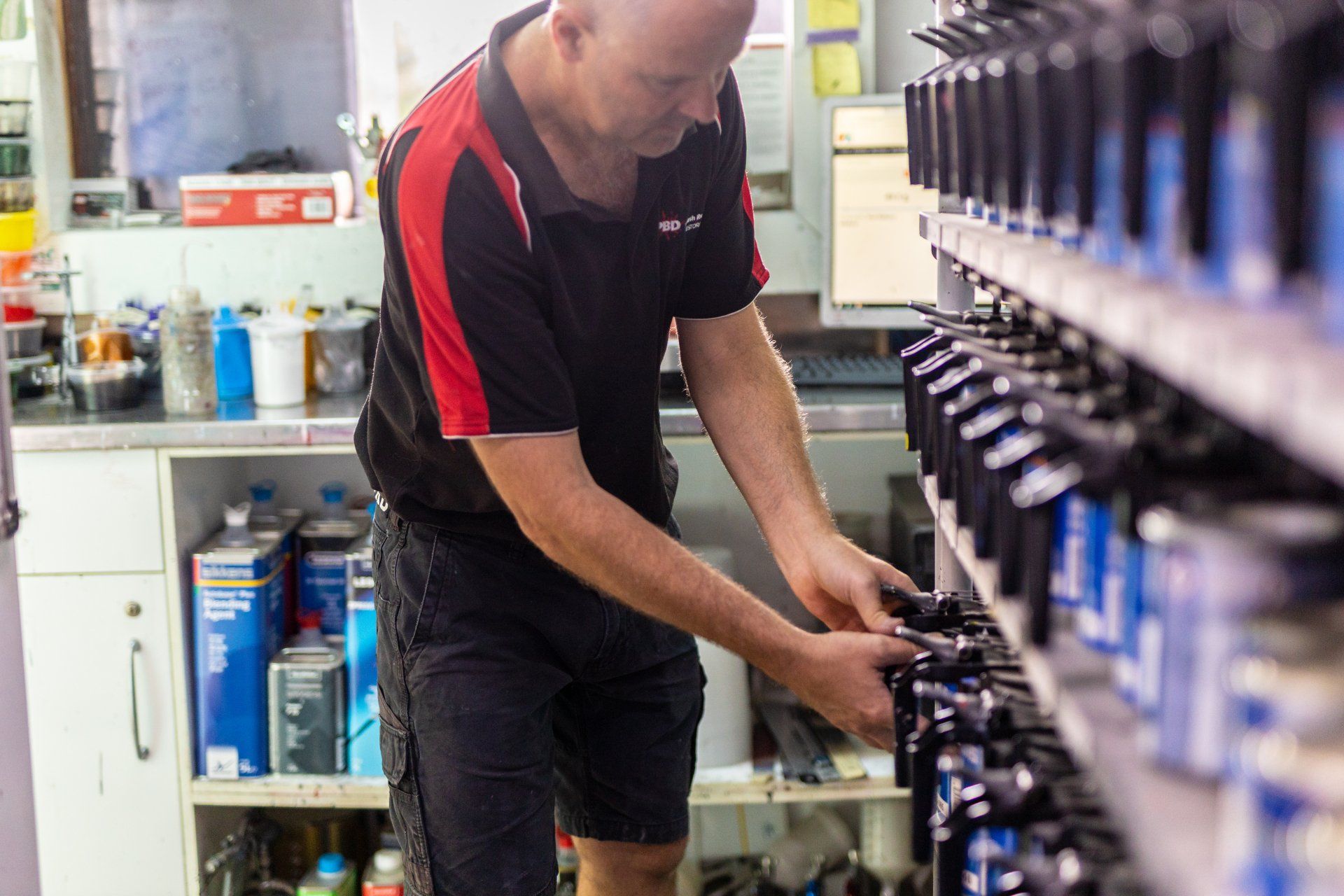 Technician adjusting equipment in a workshop aisle beside rows of machines