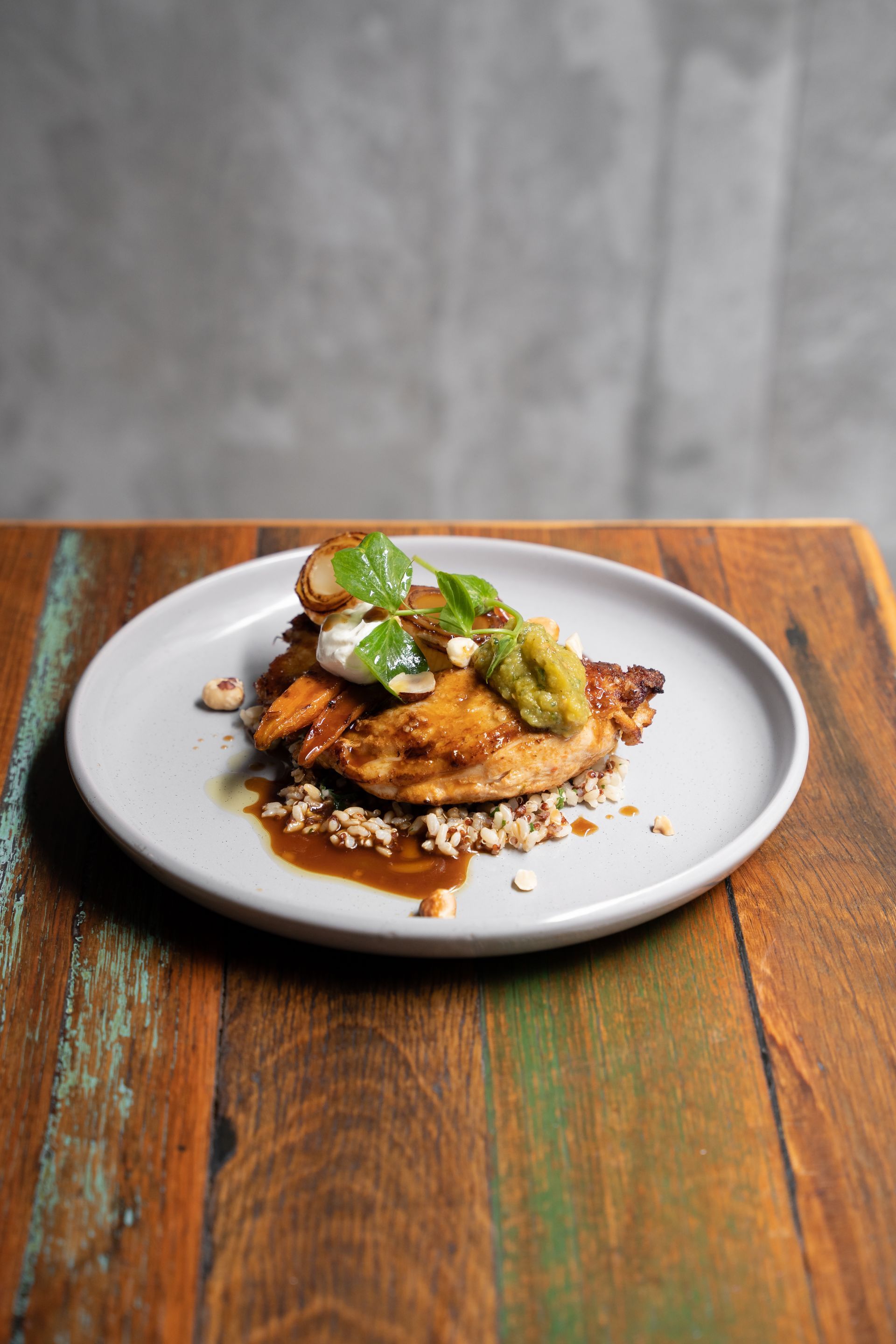 Plated dish with greens on a rustic wooden table against a gray backdrop