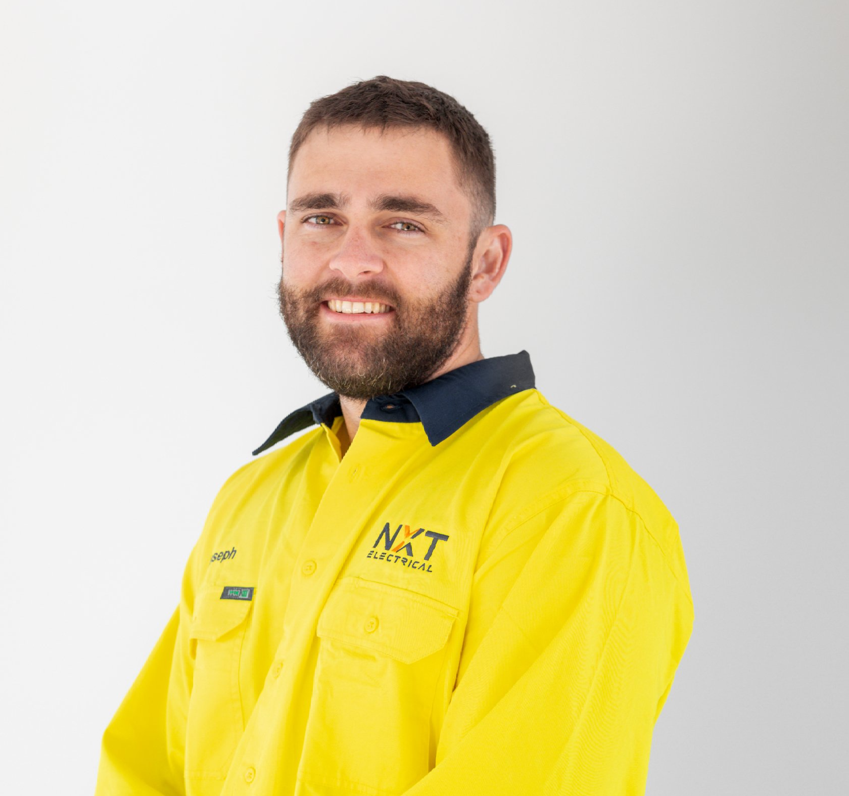Smiling man in a bright yellow work shirt against a white background