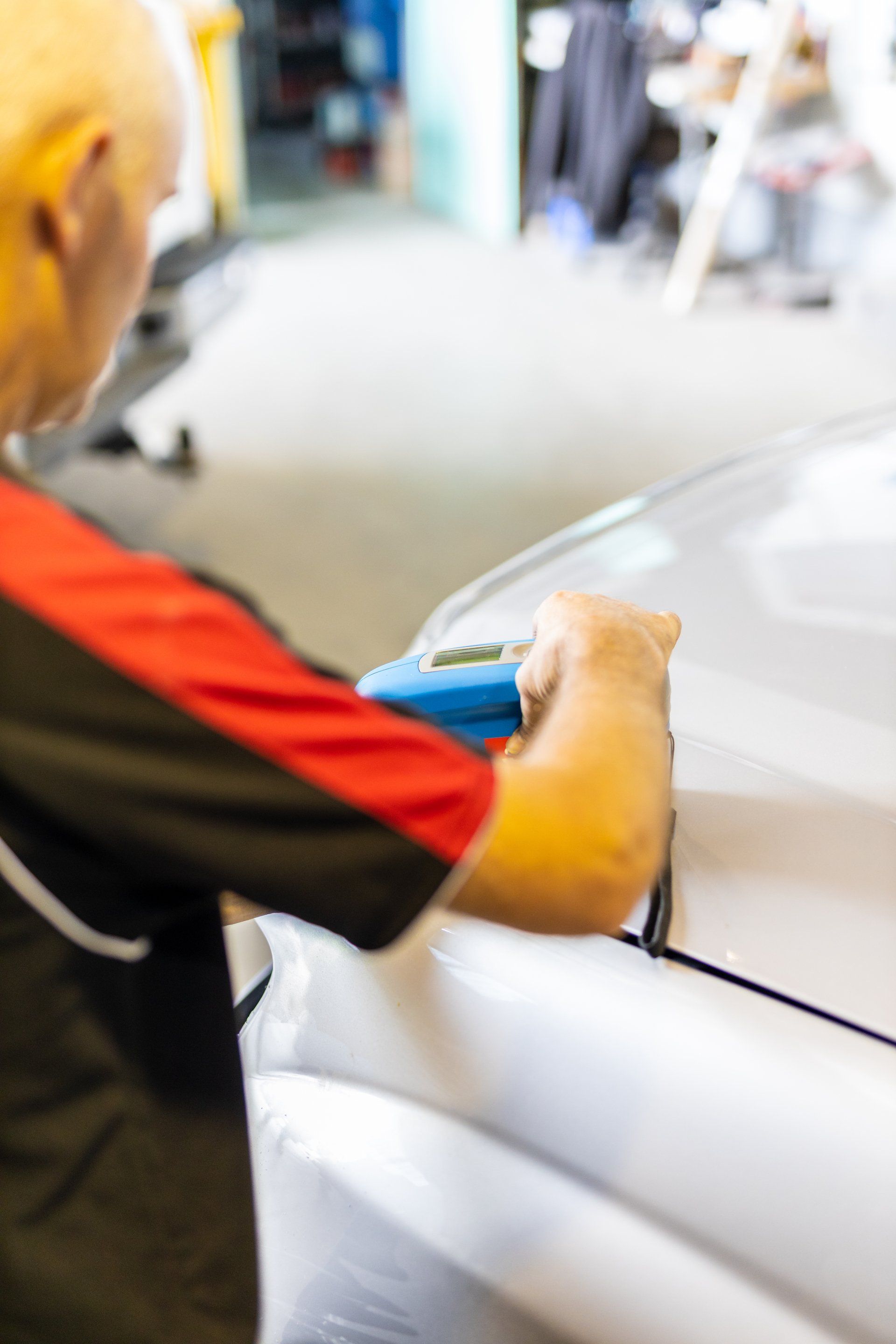 Person polishing a white car with a blue cloth in a garage