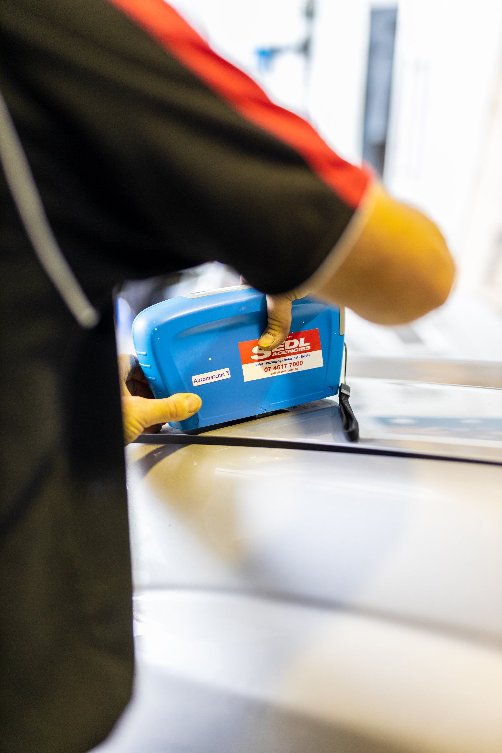Close-up of a person using a blue tape dispenser on a white surface