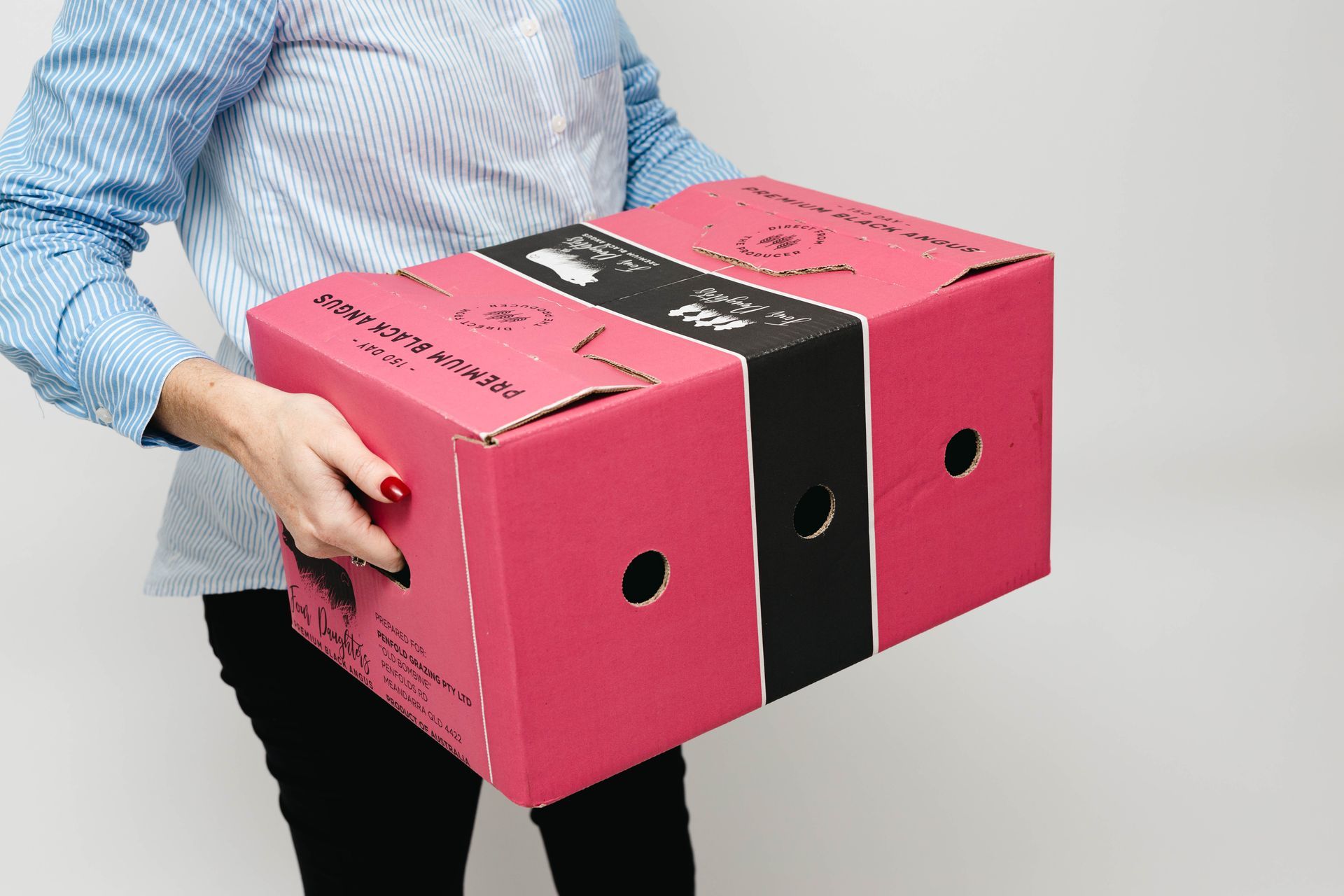 Person holding a pink and black cardboard box with round cutout holes