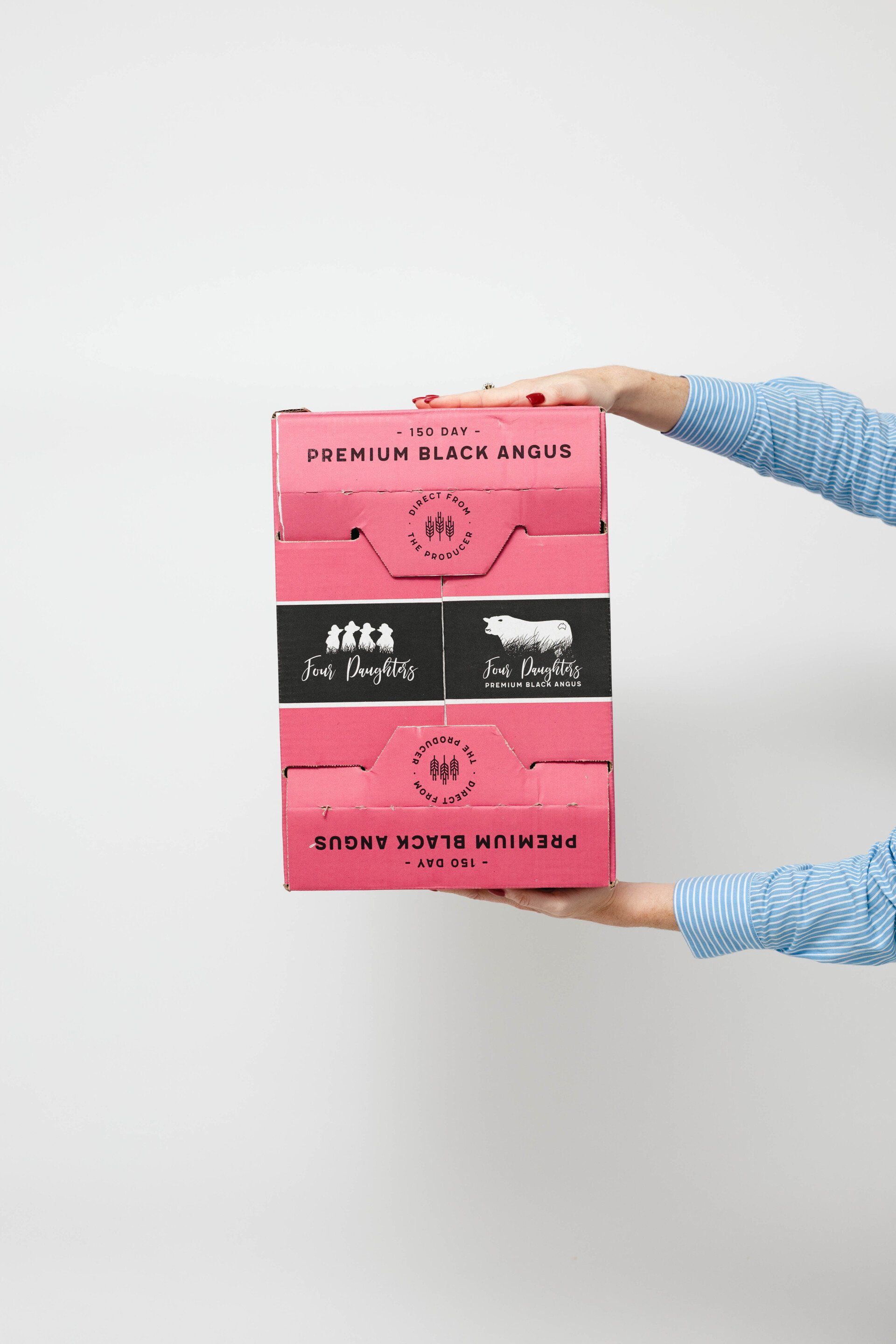 Hands in blue gloves holding a pink-and-black striped food package against a white background