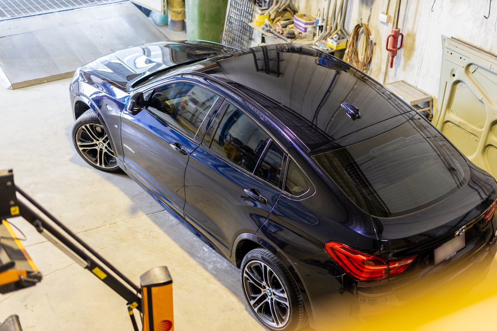 Dark blue sedan parked in a garage, viewed from above.