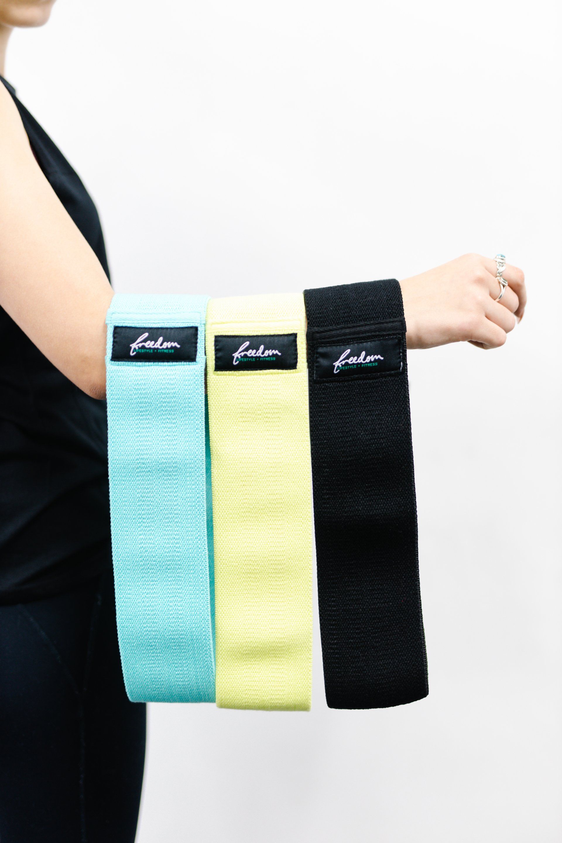 Three colorful hanging wrist straps in turquoise, yellow, and black on a person’s arm