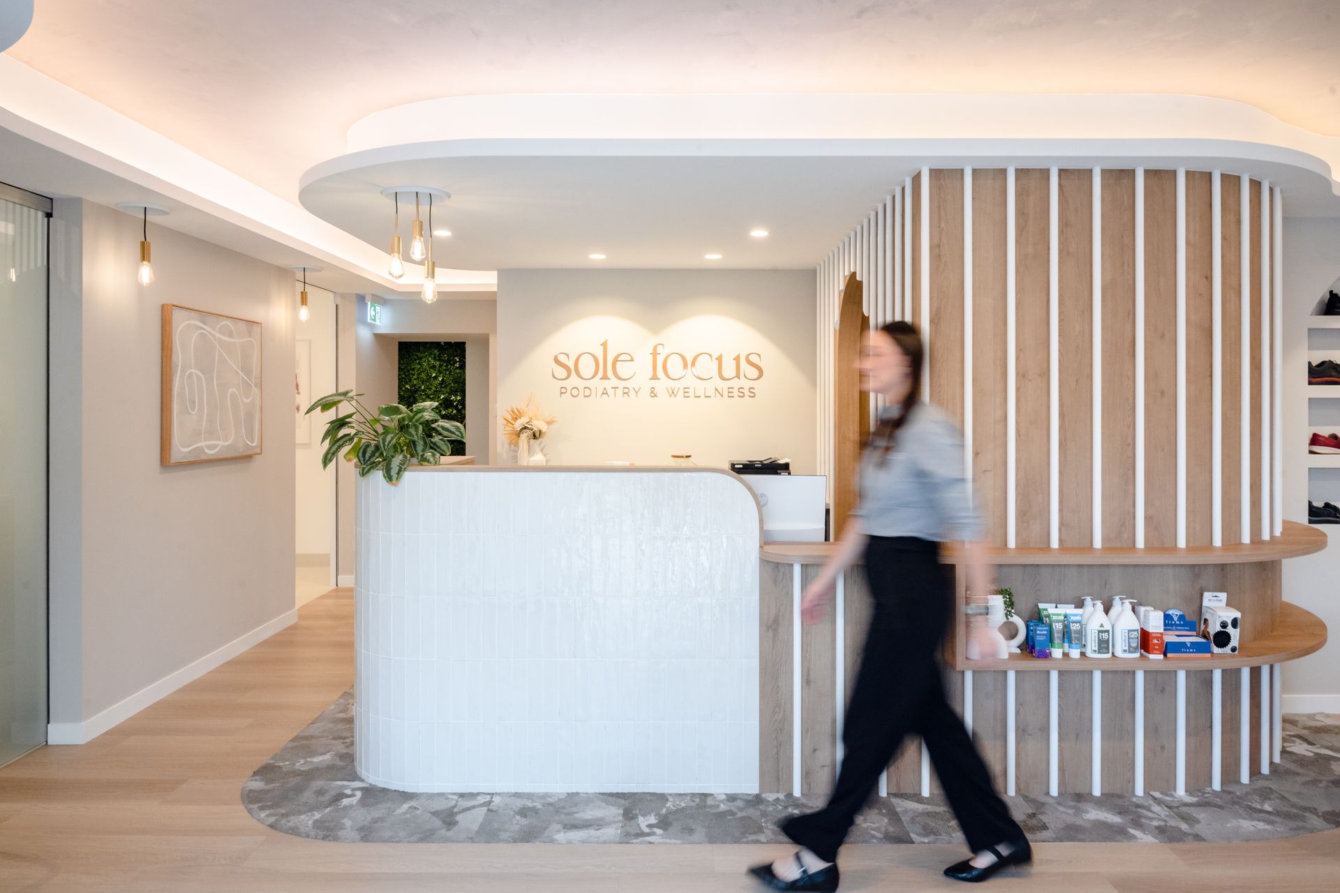 Modern white reception area with a blurred person walking past a curved front desk