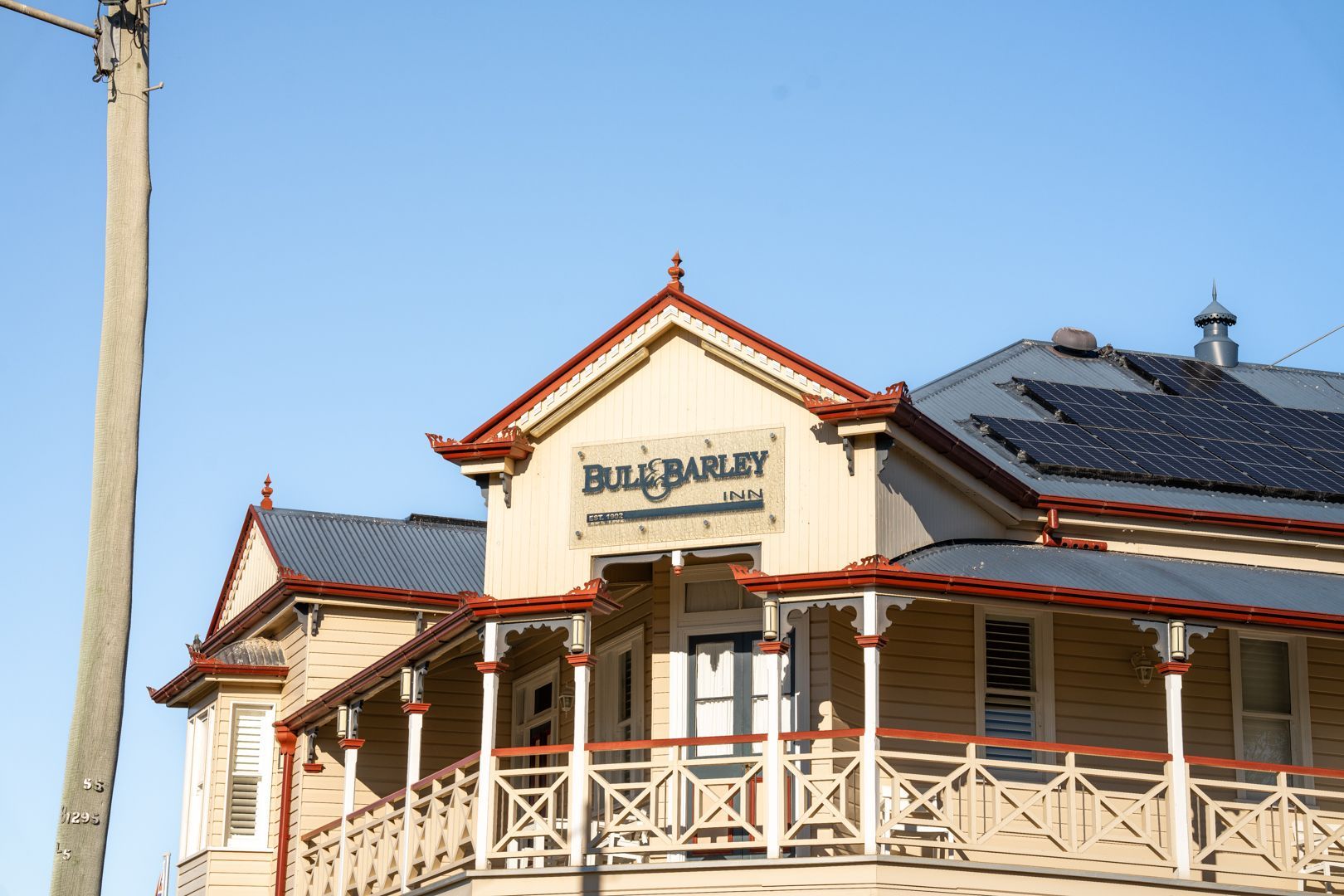 Historic beige building with red trim and blue roof under a clear sky, sign reading “Bunbury.”