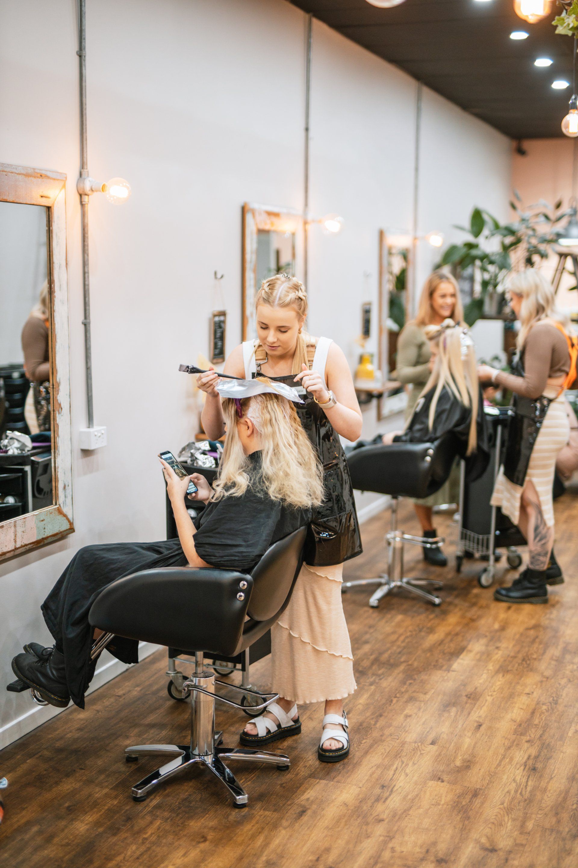 Hair salon with a stylist cutting a client’s hair in a mirror-lined station