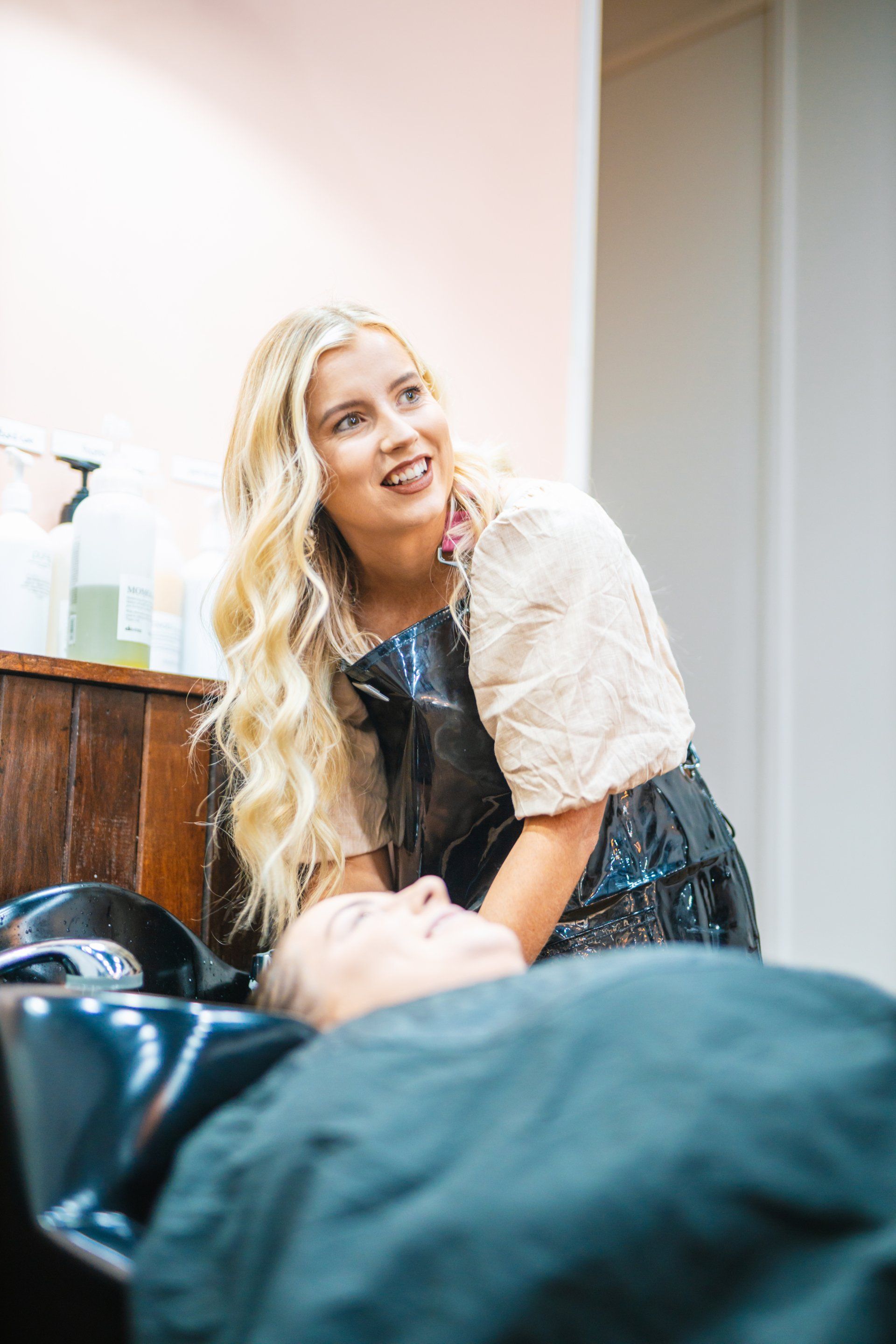 Smiling woman leaning over a person on a massage table in a bright spa room