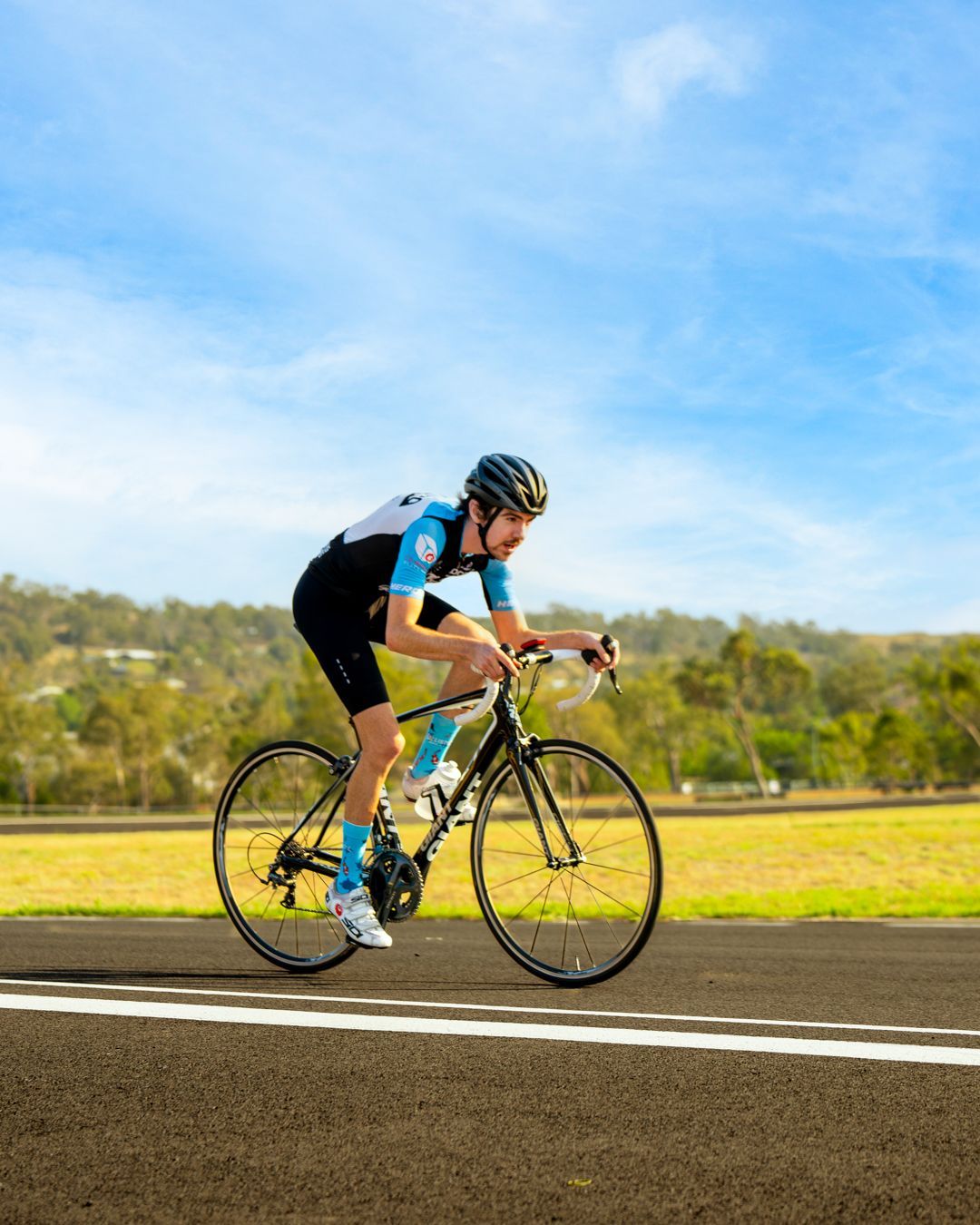 Cyclist in blue jersey racing on a road under a bright sky