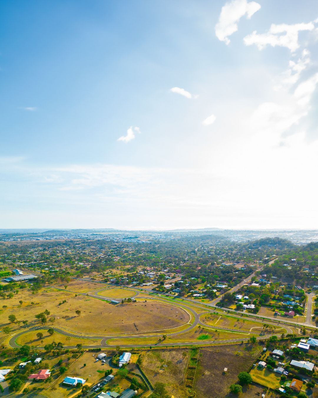 Aerial view of a rural town with fields, scattered houses, and a bright blue sky