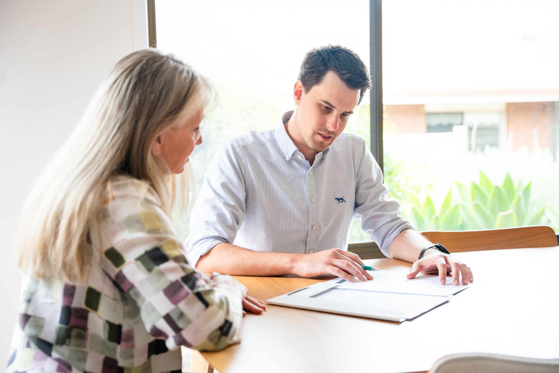 Two people reviewing documents at a bright office table