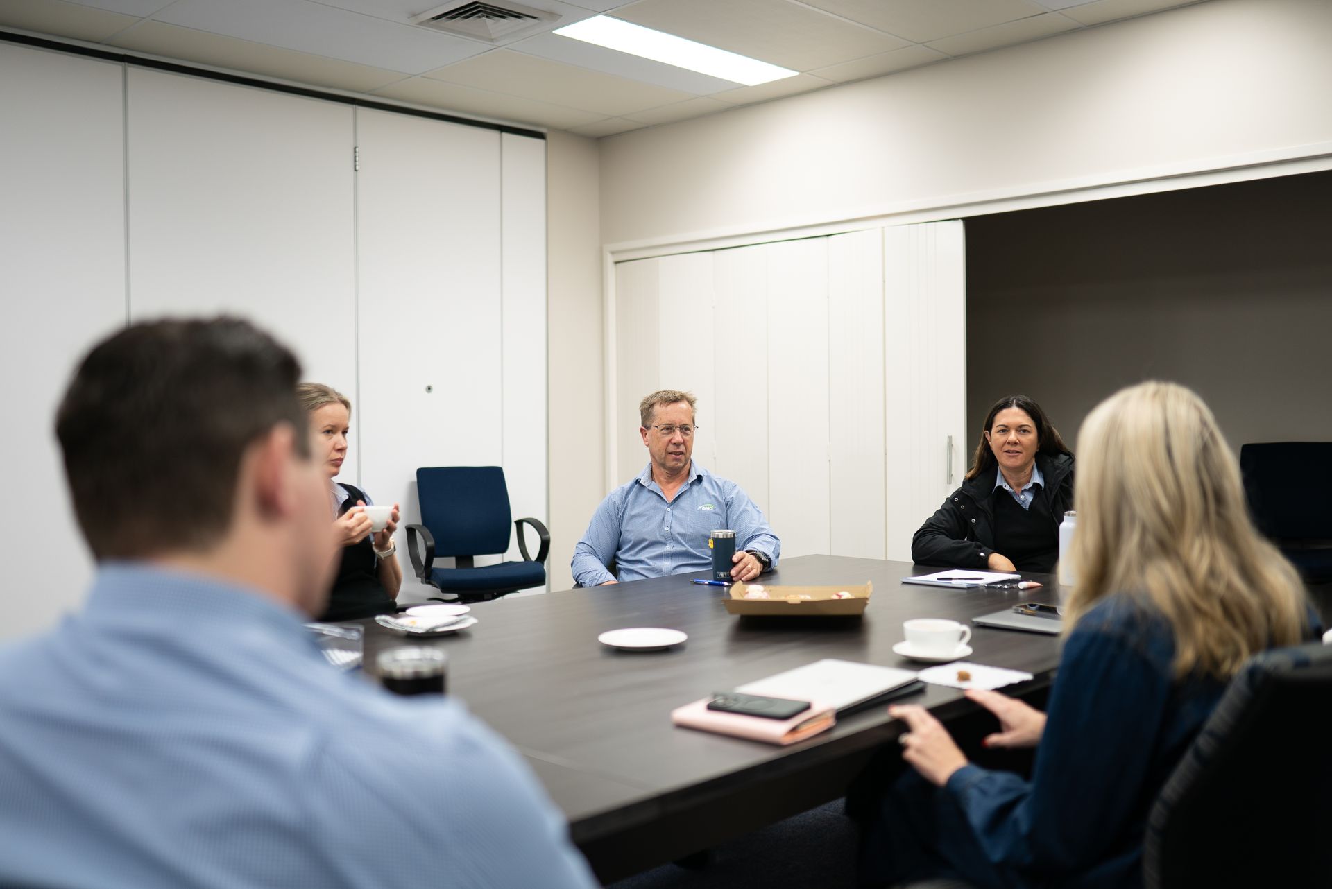 People seated around a conference table in a meeting room, discussing documents and laptops.