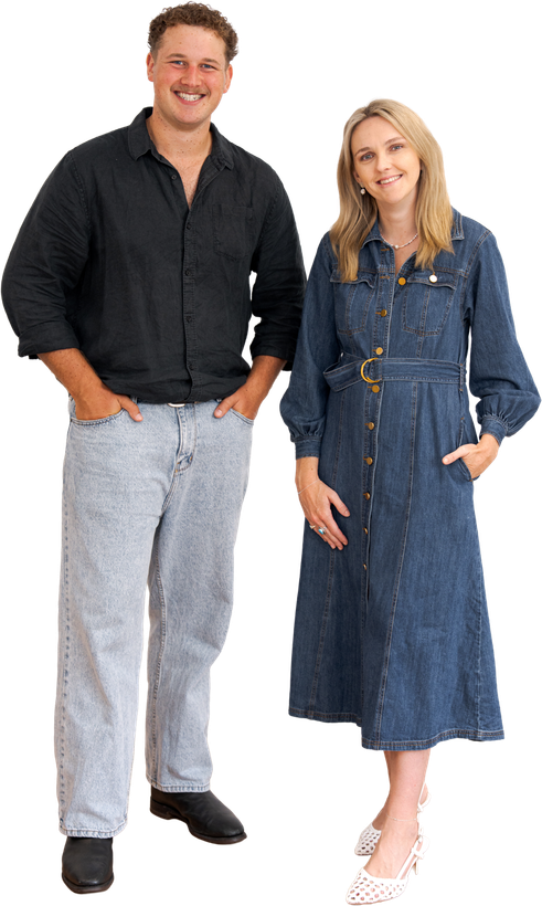 Two people posing in casual clothes, a man in a black shirt and gray pants beside a woman in a denim dress.