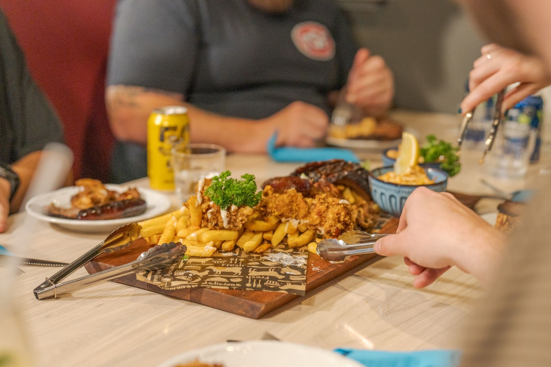 Table with a tray of fries and bread at a casual restaurant, with people eating in the background