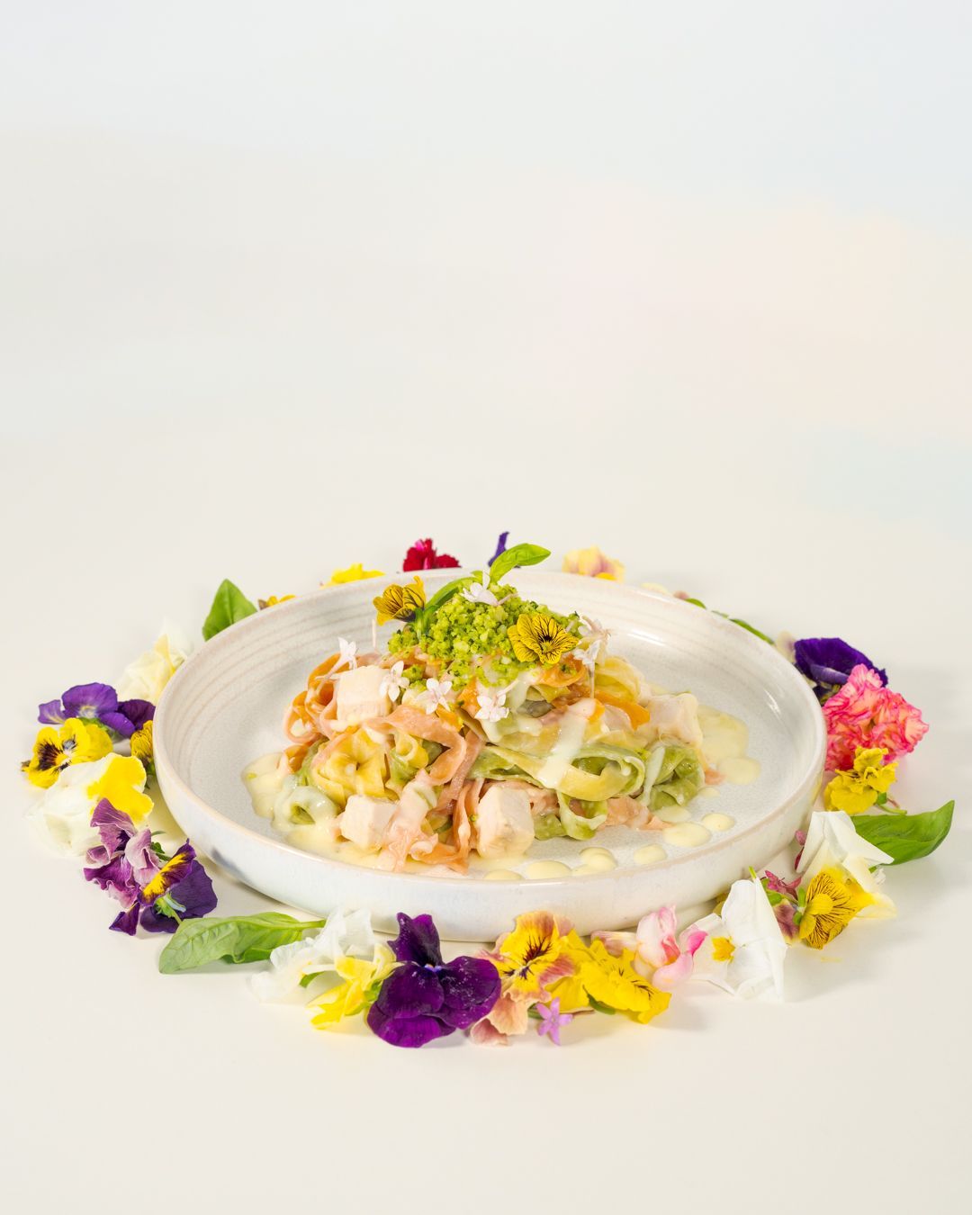 Elegant seafood salad in a white bowl, garnished with herbs and surrounded by colorful edible flowers