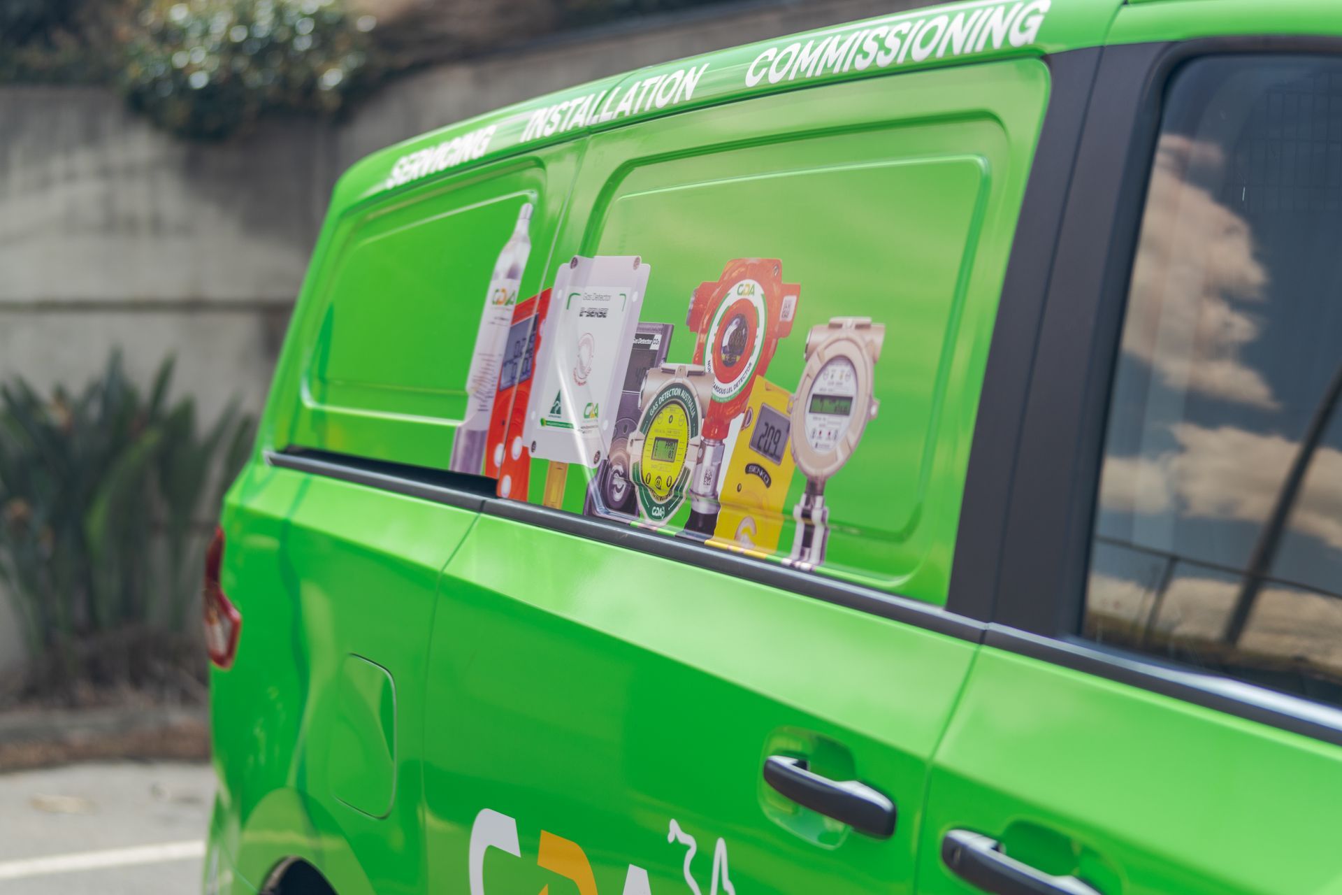 Bright green van with colorful stickers parked outdoors near a wall