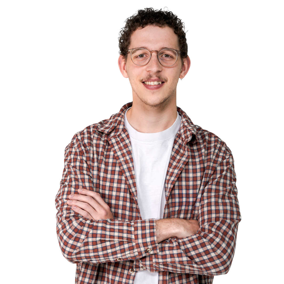 Smiling person with glasses and curly hair, wearing a plaid shirt over a white T-shirt, arms crossed against a white background