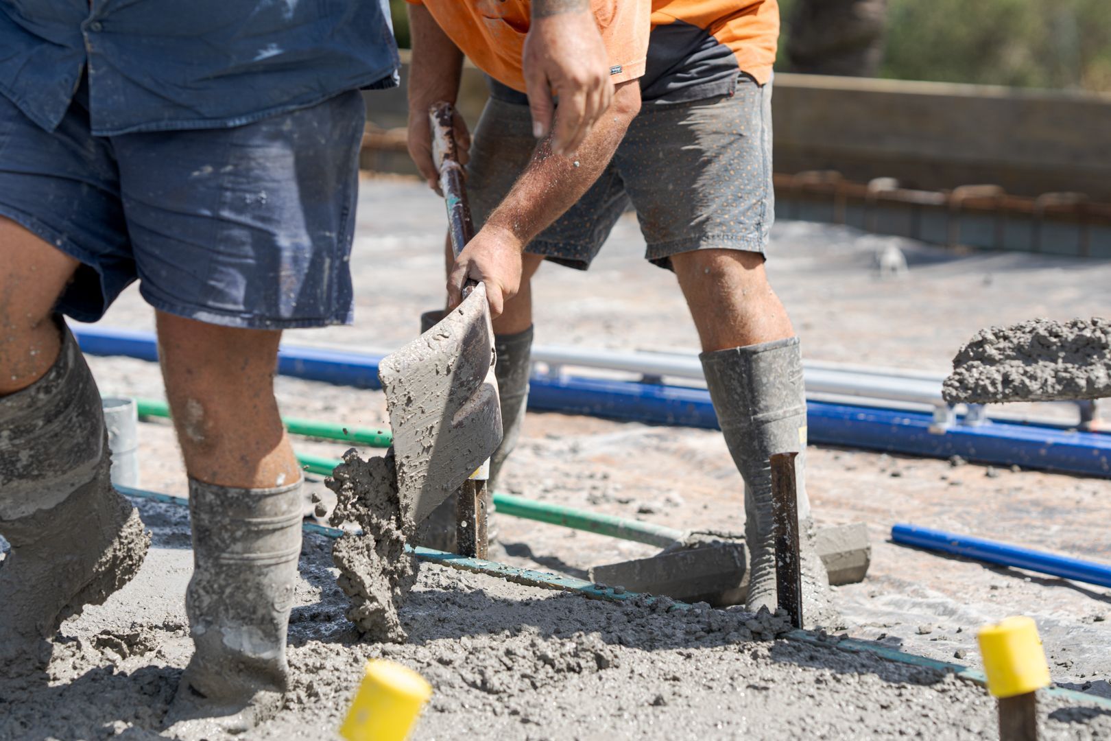 Workers pouring and smoothing wet concrete at a construction site