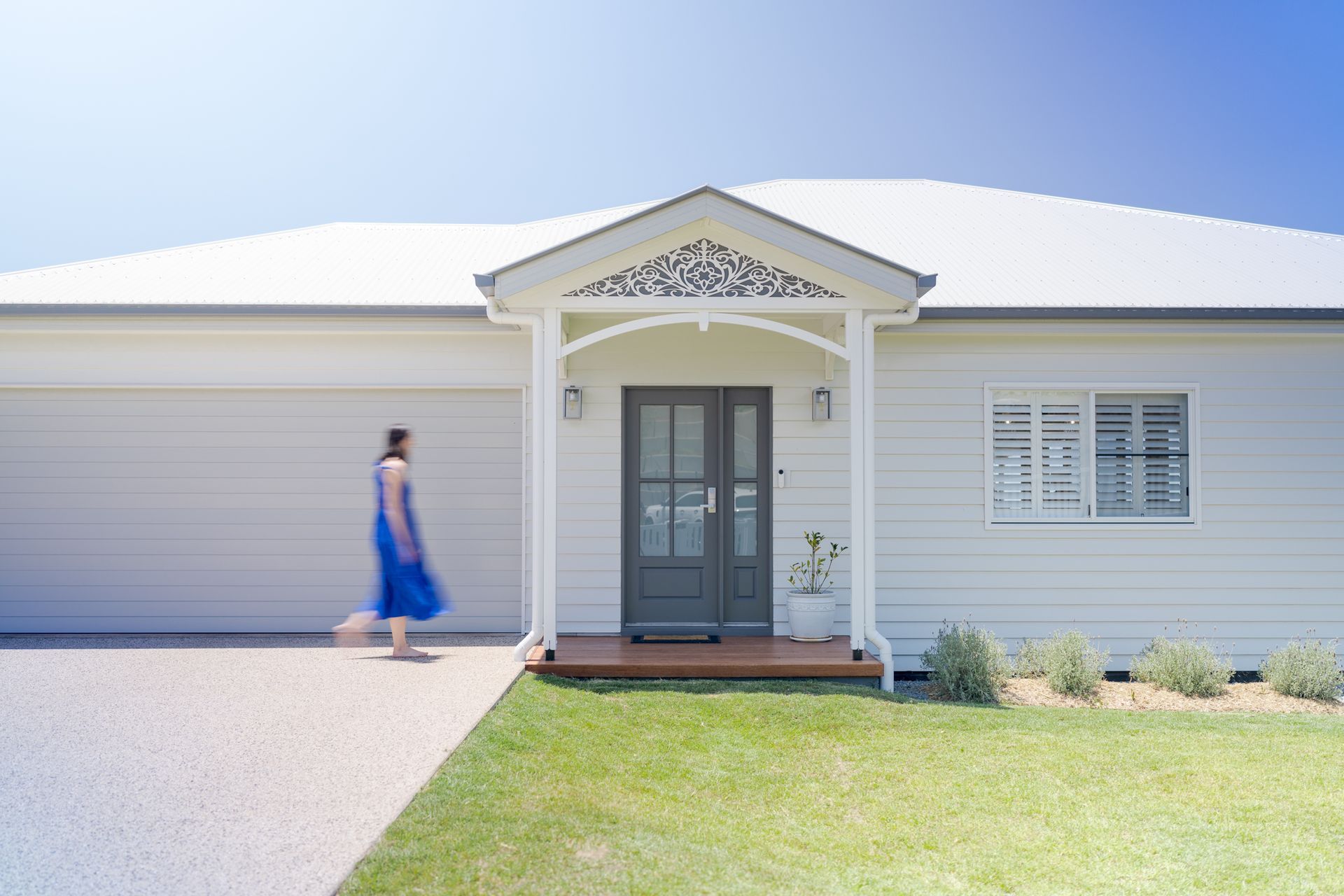 Modern white house exterior with a person walking past the front entrance