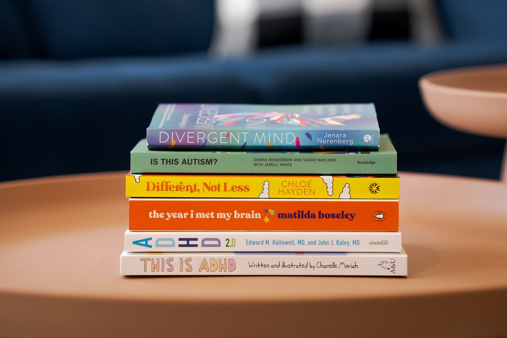 Stack of colorful books on a table in front of a blurred blue couch