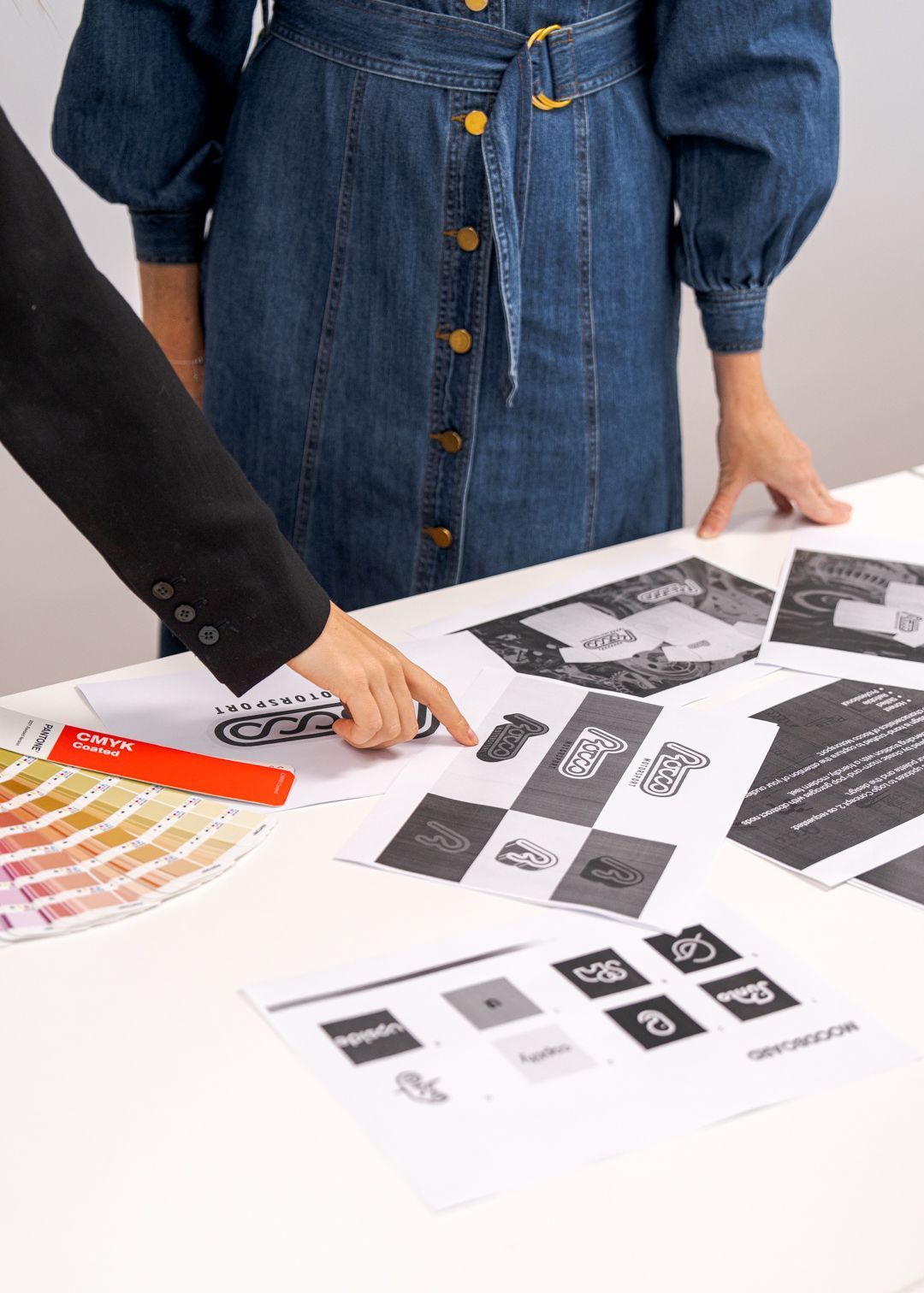 Two people reviewing printed design mockups and color swatches on a white table