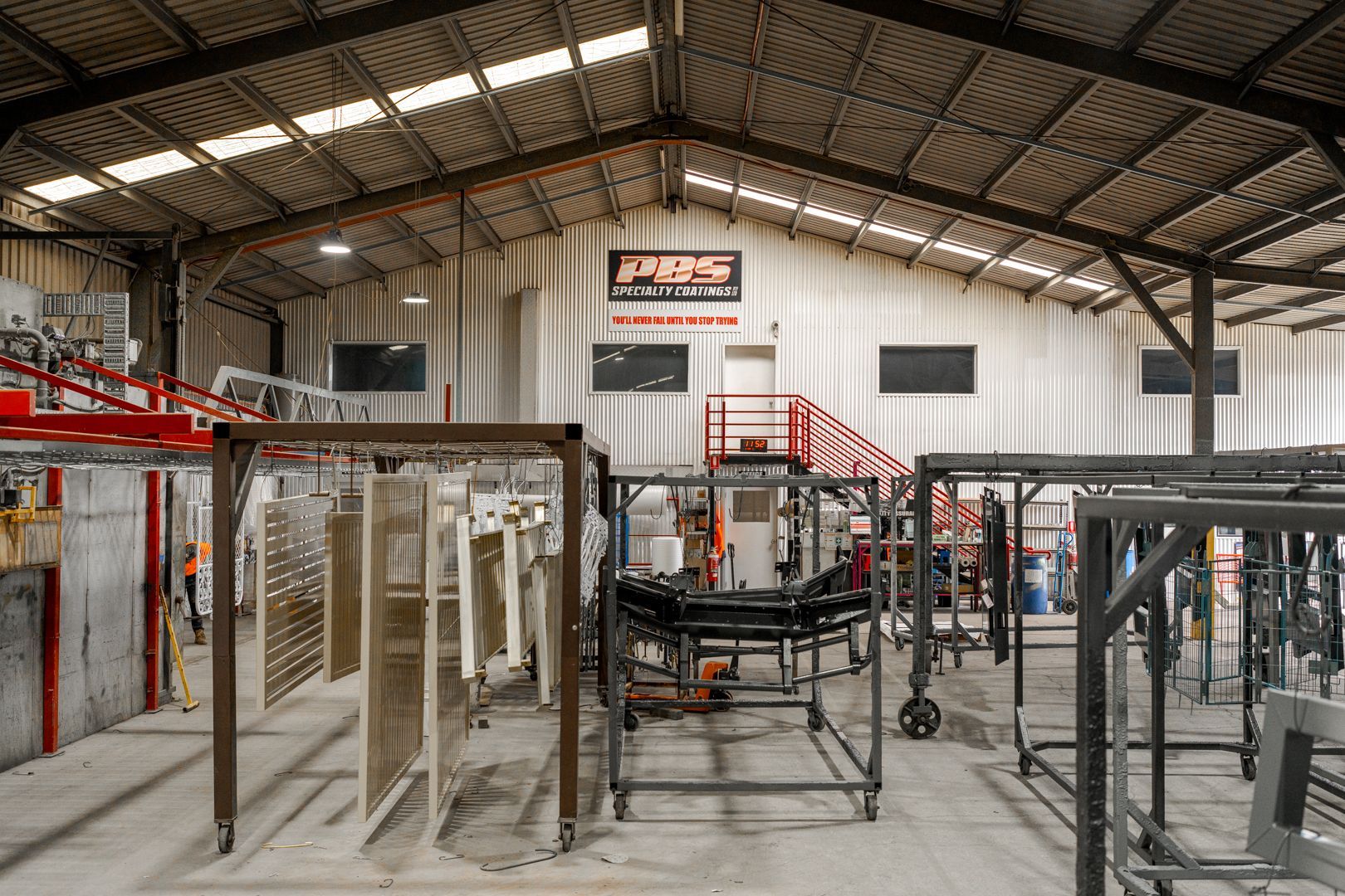 Industrial workshop interior with metal frames, machinery, and tools under a high roof