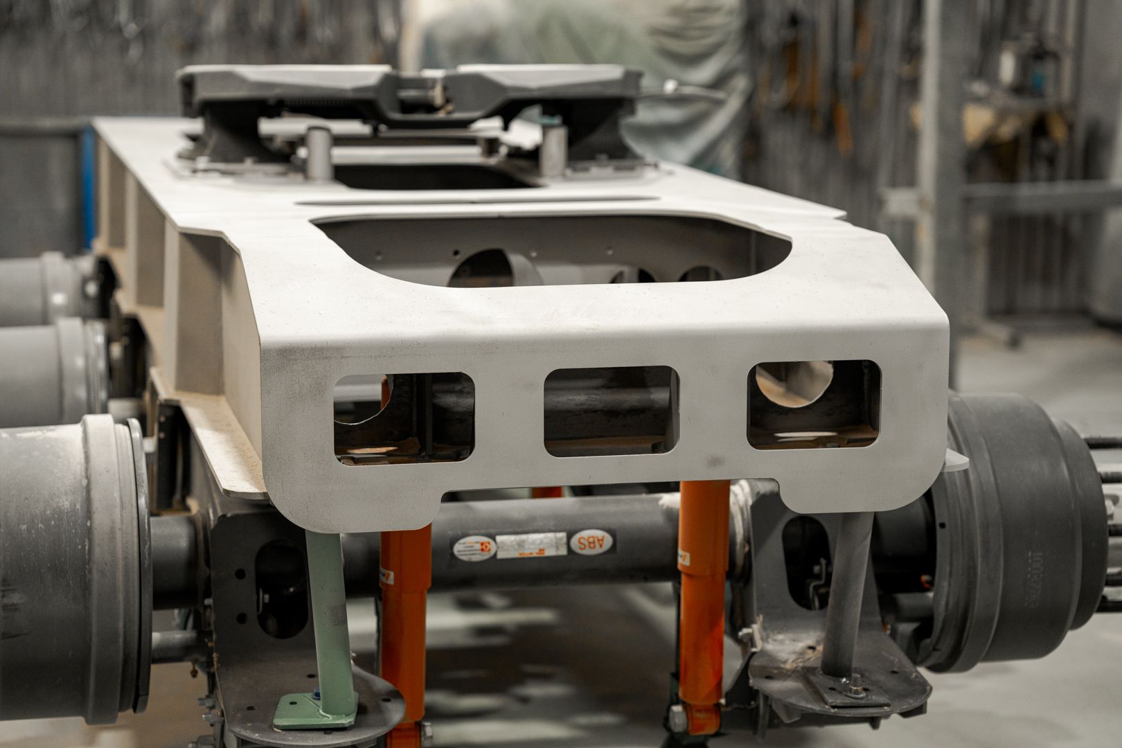 White industrial machine component with black rollers in a factory setting