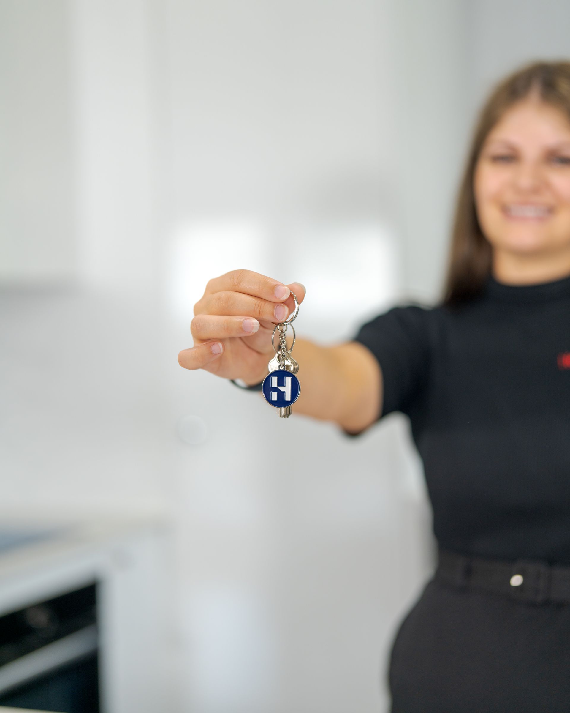 Woman holding up a blue keychain in a bright kitchen