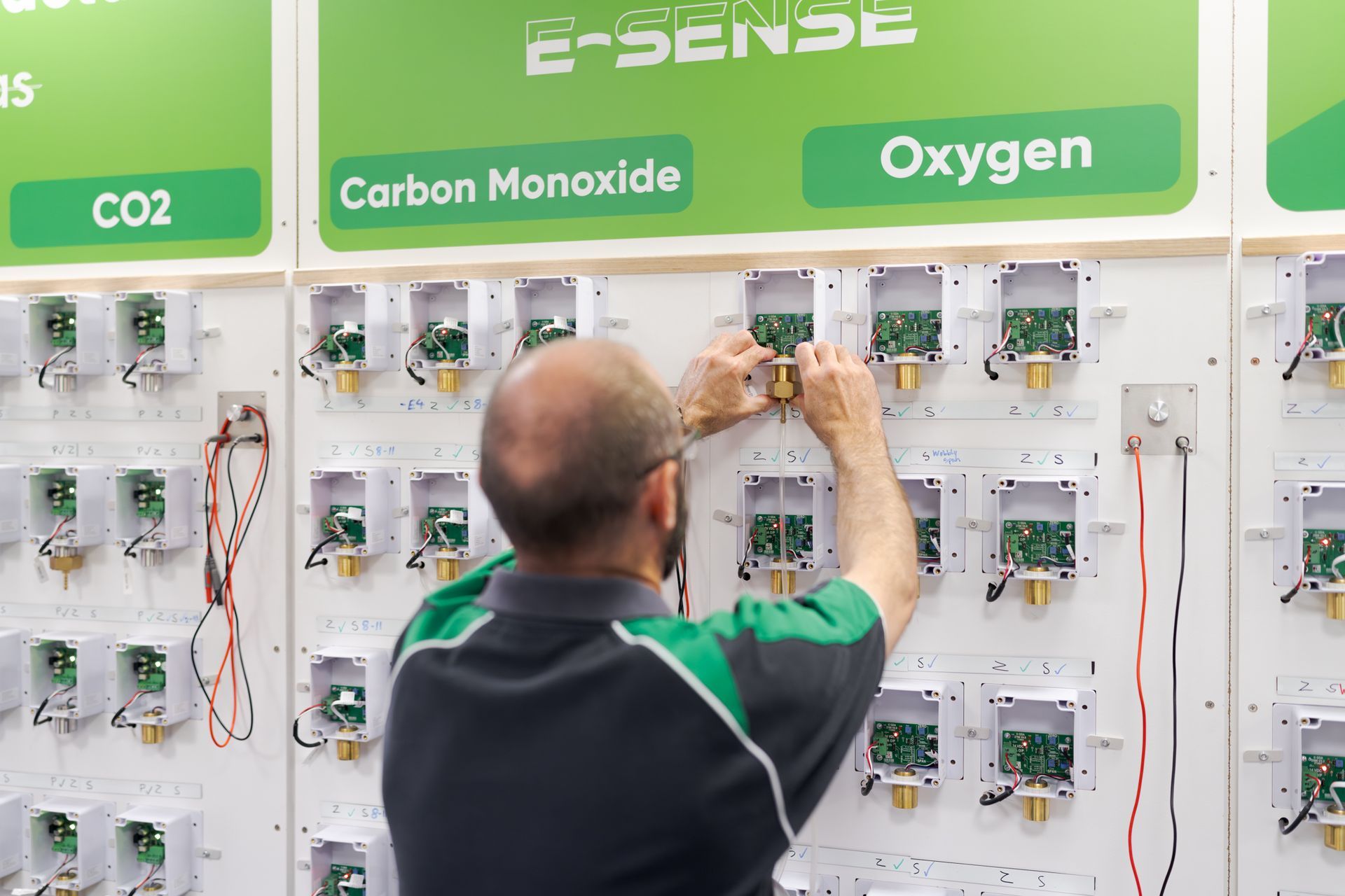 Technician adjusting controls on a wall display of oxygen, carbon monoxide, and CO2 monitors