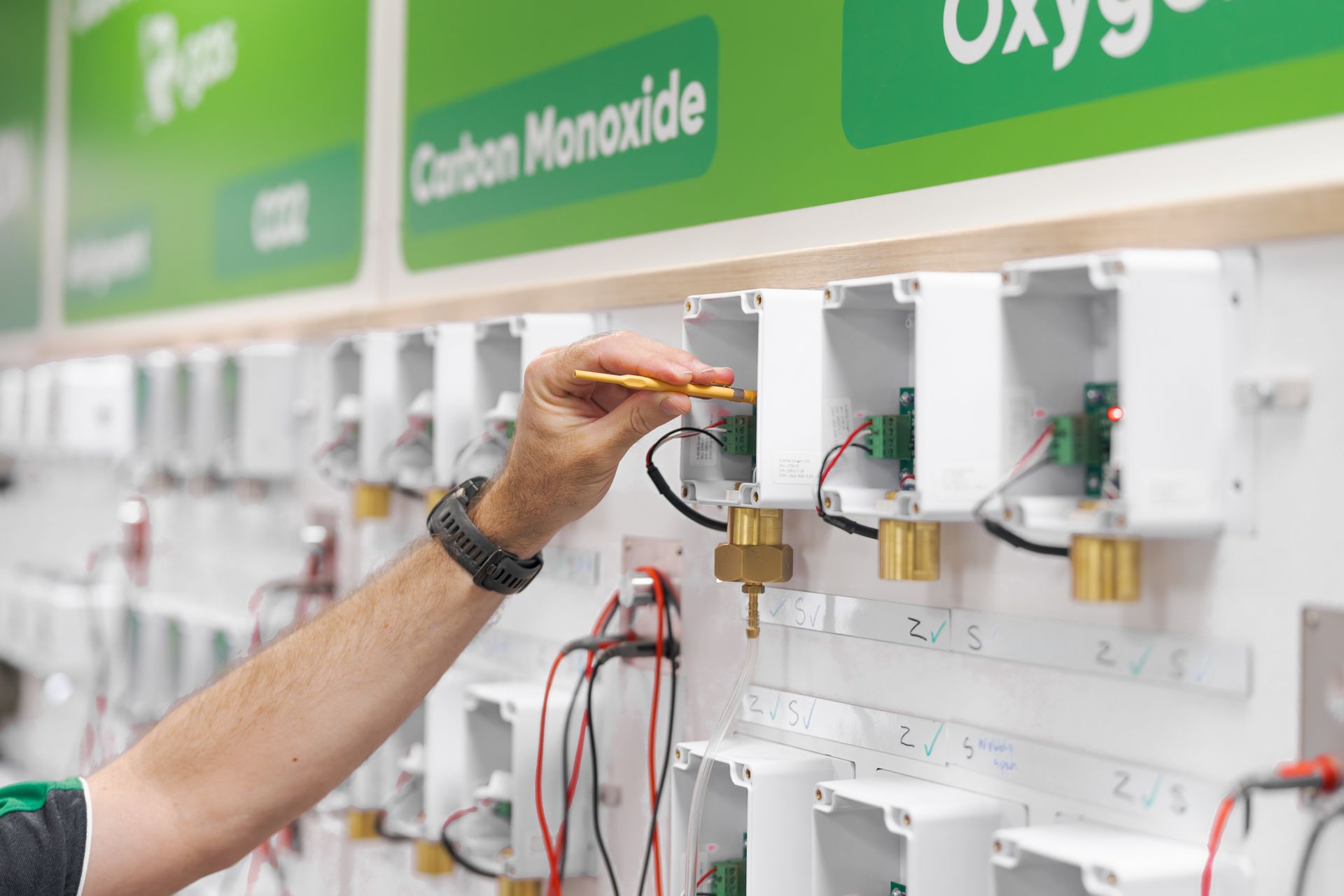 Hand adjusting oxygen and carbon monoxide gas control valves on a wall-mounted medical gas panel