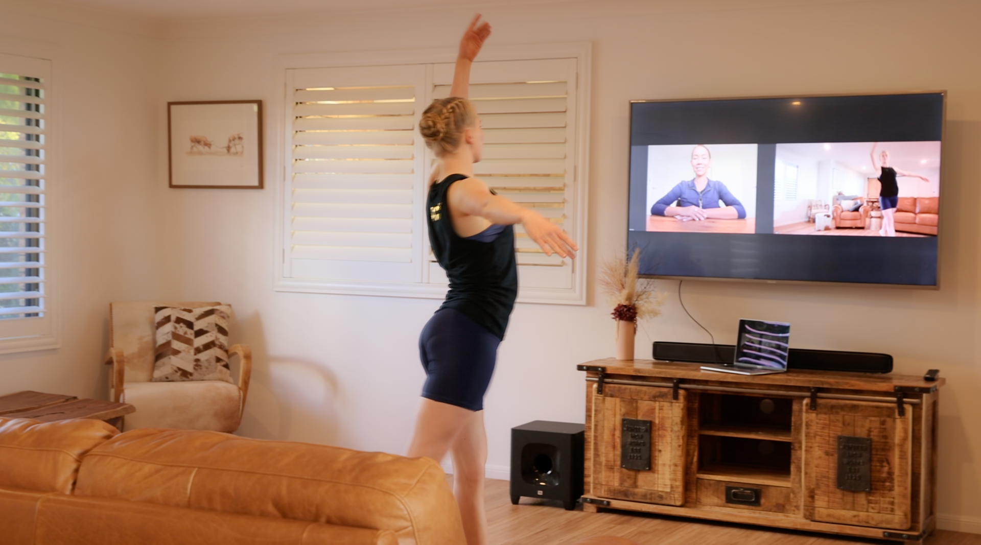 Woman stretching in a living room while watching a TV workout video