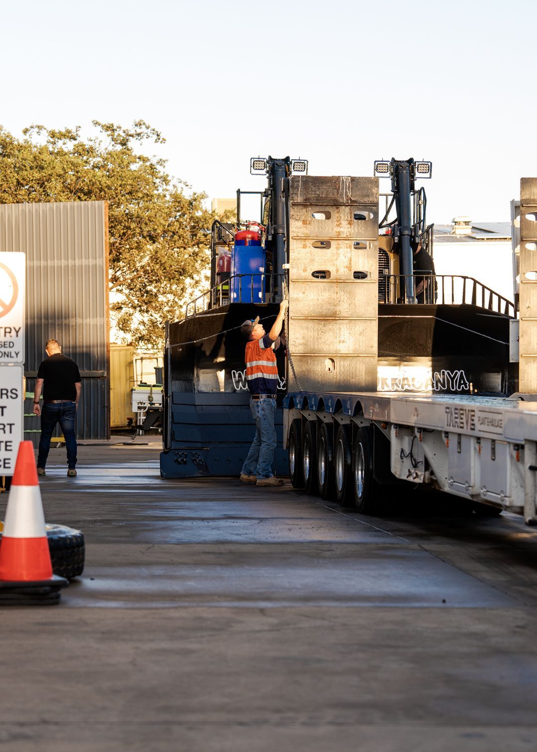 Workers loading a large truck trailer at an outdoor industrial site