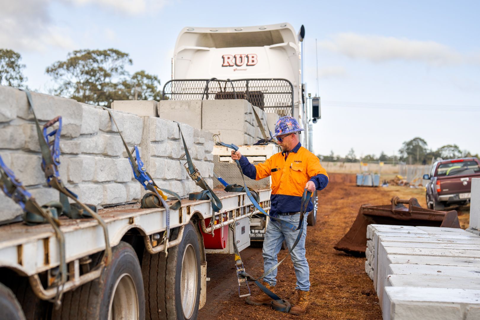 Worker in orange shirt unloading stone slabs from a truck at a construction site