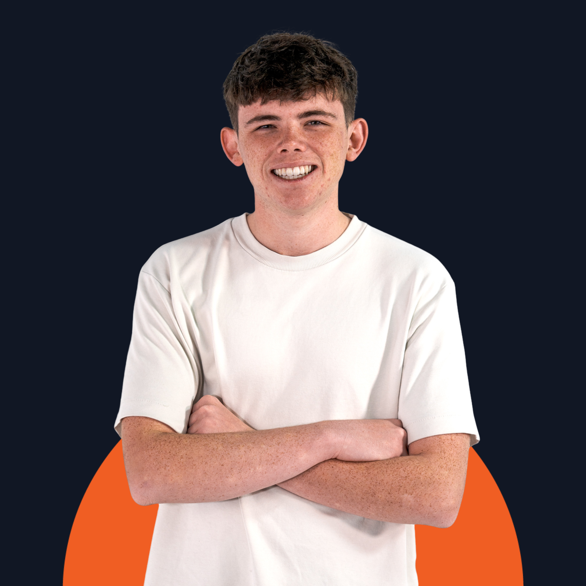 Smiling young man with arms crossed, wearing a white shirt against a dark background with an orange shape below.