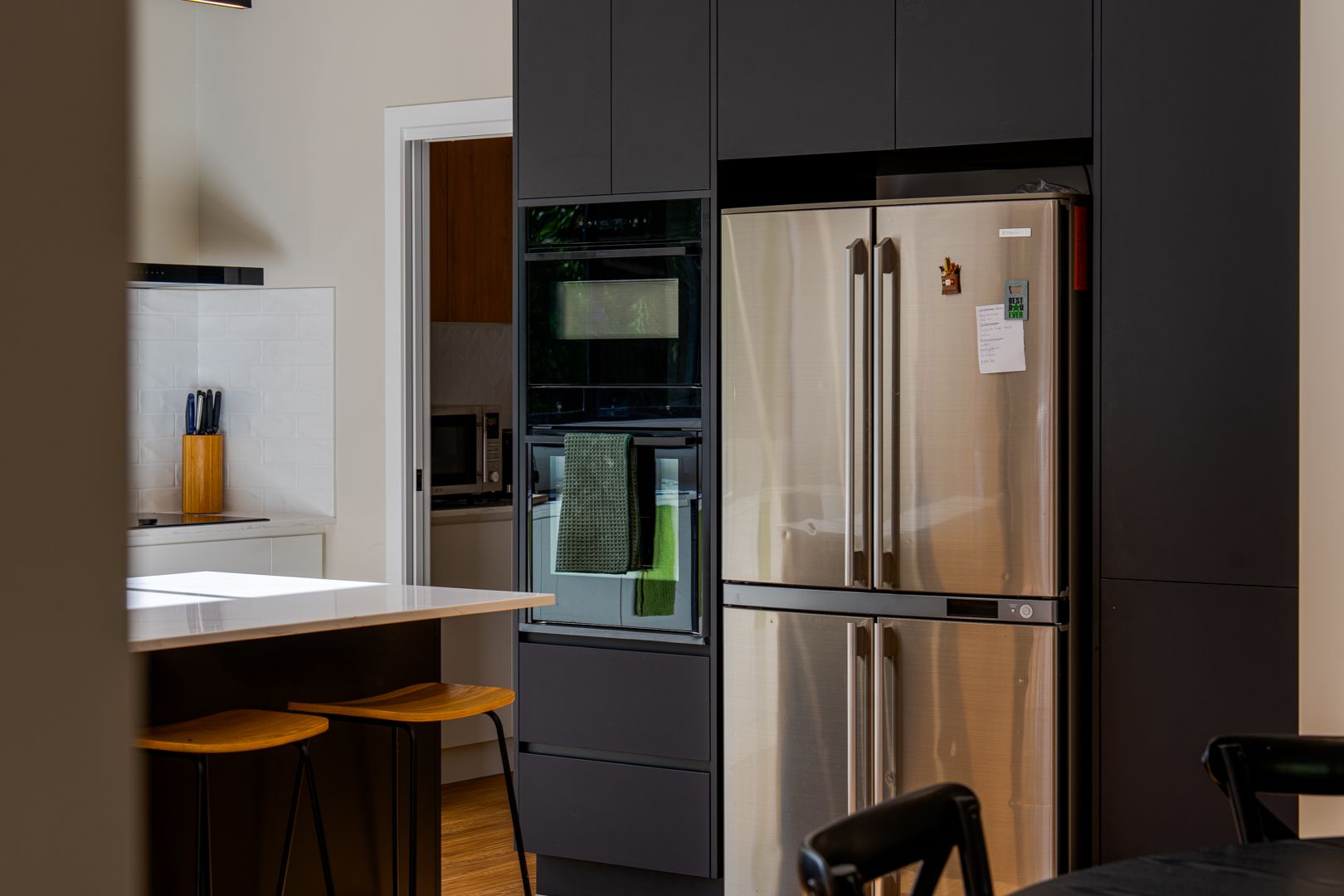 Modern kitchen with stainless steel refrigerator, built-in oven, and white countertop