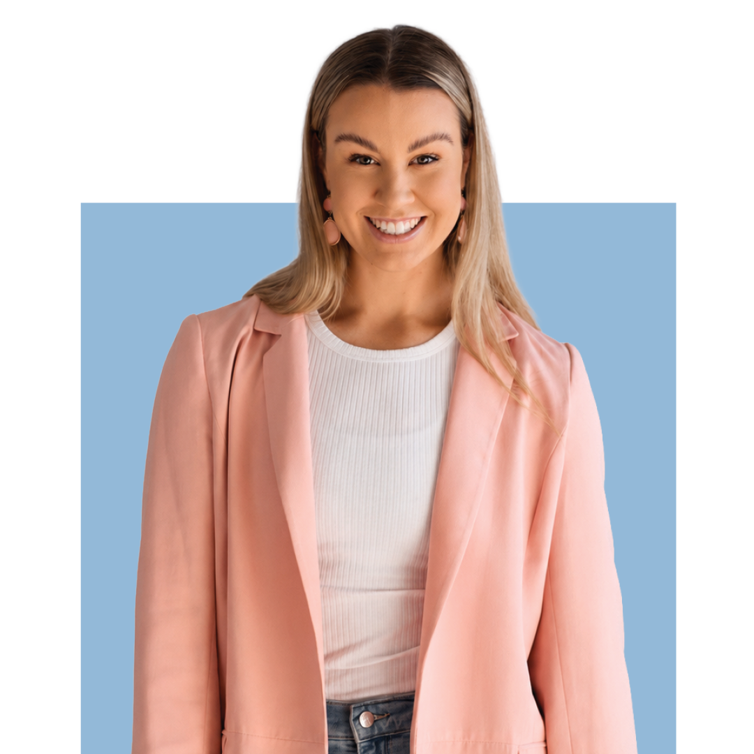 Smiling person in a pink blazer over a white top, standing against a blue background.