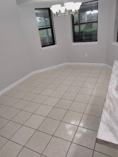 Empty dining area with tiled floor, gray walls, and two windows.