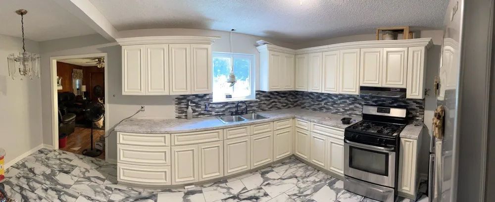 A kitchen with white cabinets, marble floors, and a stainless steel stove.