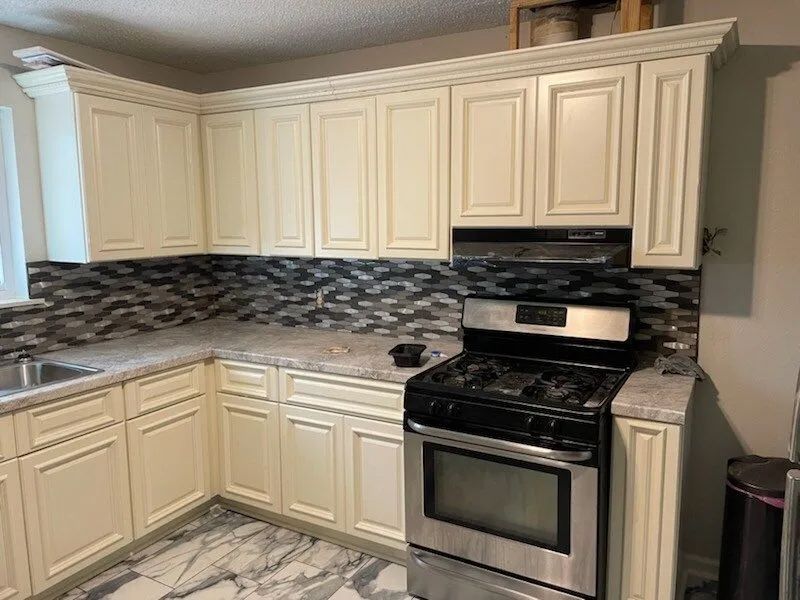 Cream-colored kitchen cabinets with a stainless steel stove.