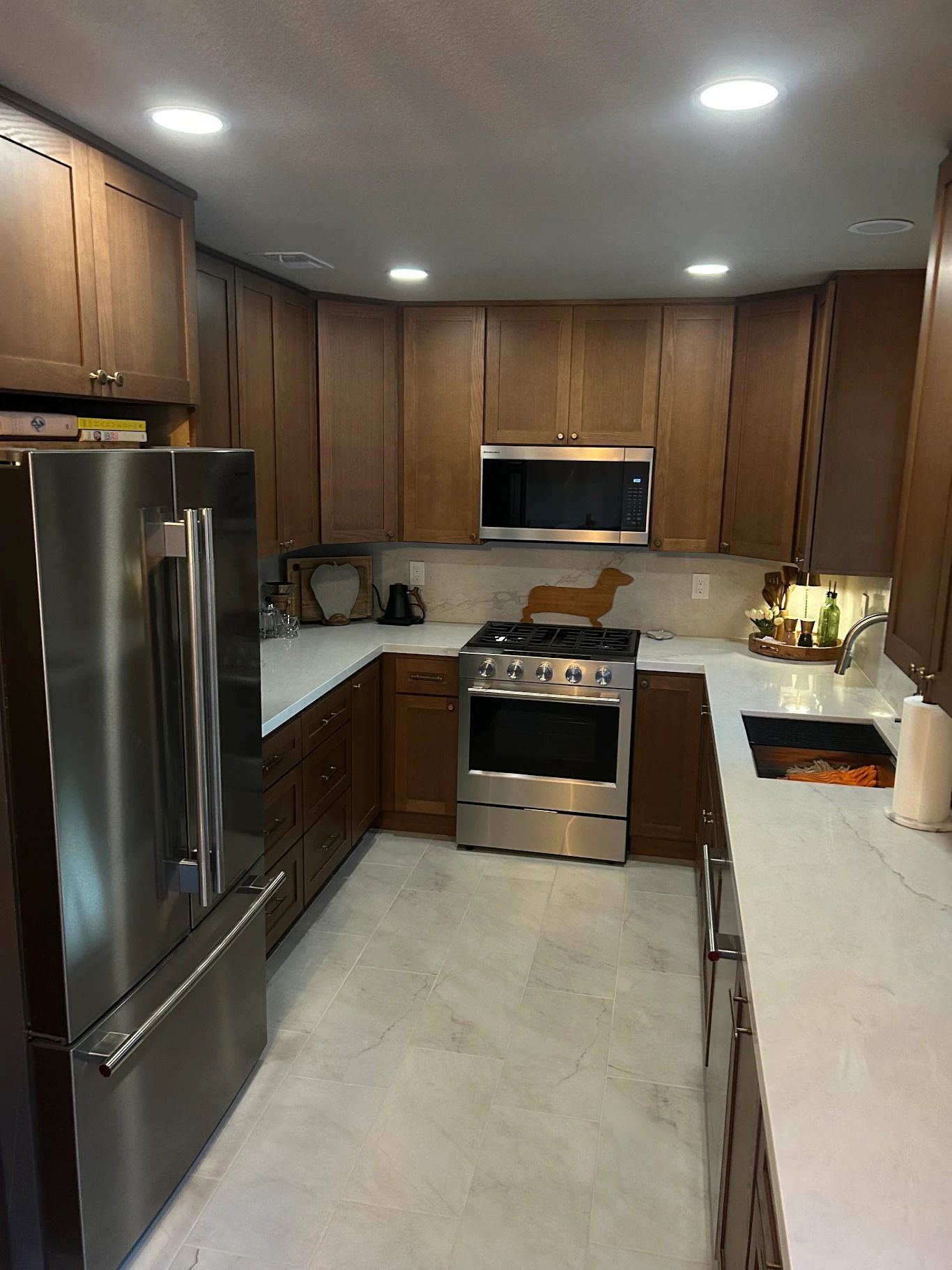 Modern kitchen by Straight Edge Builders, with stainless steel appliances, wood cabinets, and a light countertop peninsula