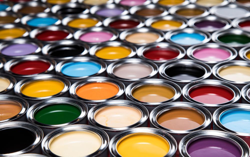 A Bunch Of Cans Of Paint Of Different Colours Are Lined Up On A Table — Yves De Wilde Quality Painting Services In Lismore, NSW
