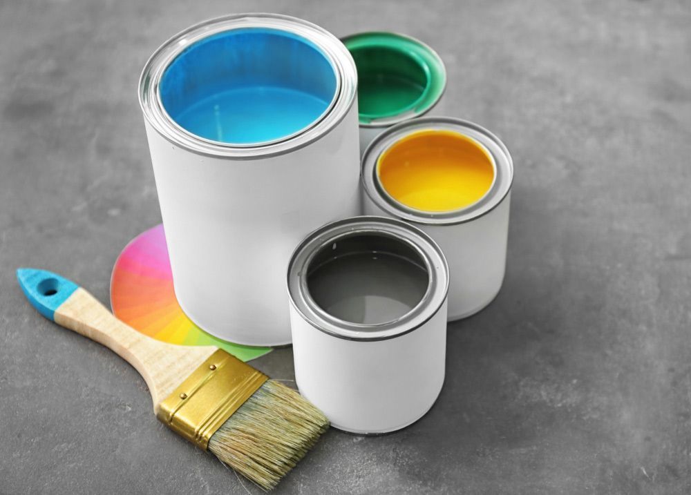 Four Cans Of Paint And A Brush On A Table — Yves De Wilde Quality Painting Services In Ballina, NSW